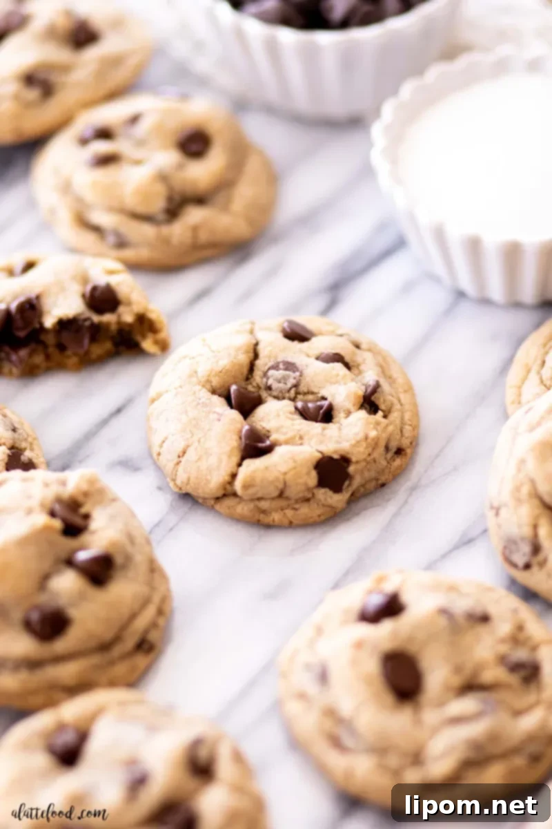 A stunning array of freshly baked chocolate chip cookies arranged on a marble board, highlighting their perfect golden brown edges and generous chocolate chip distribution. This recipe uses vanilla extract, espresso powder, and brown sugar for superior flavor and texture.