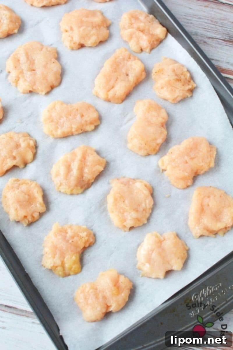Essential Freezing Step for Homemade McDonald's Chicken Nuggets Frozen ground chicken nuggets neatly arranged on parchment paper before breading