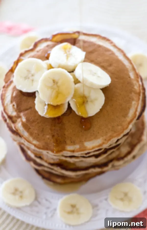 Cloud-Like Honey Banana Pancakes 8 A stack of delicious fluffy honey banana pancakes with a side of syrup and fresh bananas
