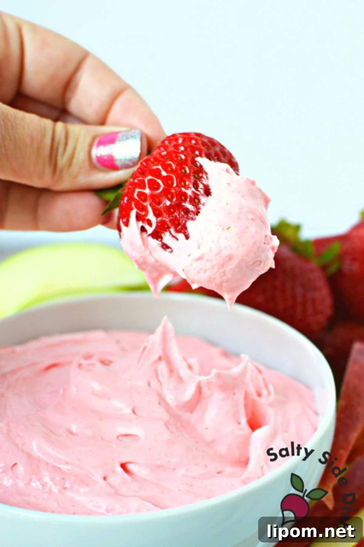 Luscious Strawberry Dip 2 A vibrant bowl of homemade strawberry fruit dip being perfectly scooped by a fresh, ripe strawberry, showcasing its creamy texture and appealing pink hue, ready for a delightful summer snack or party appetizer.