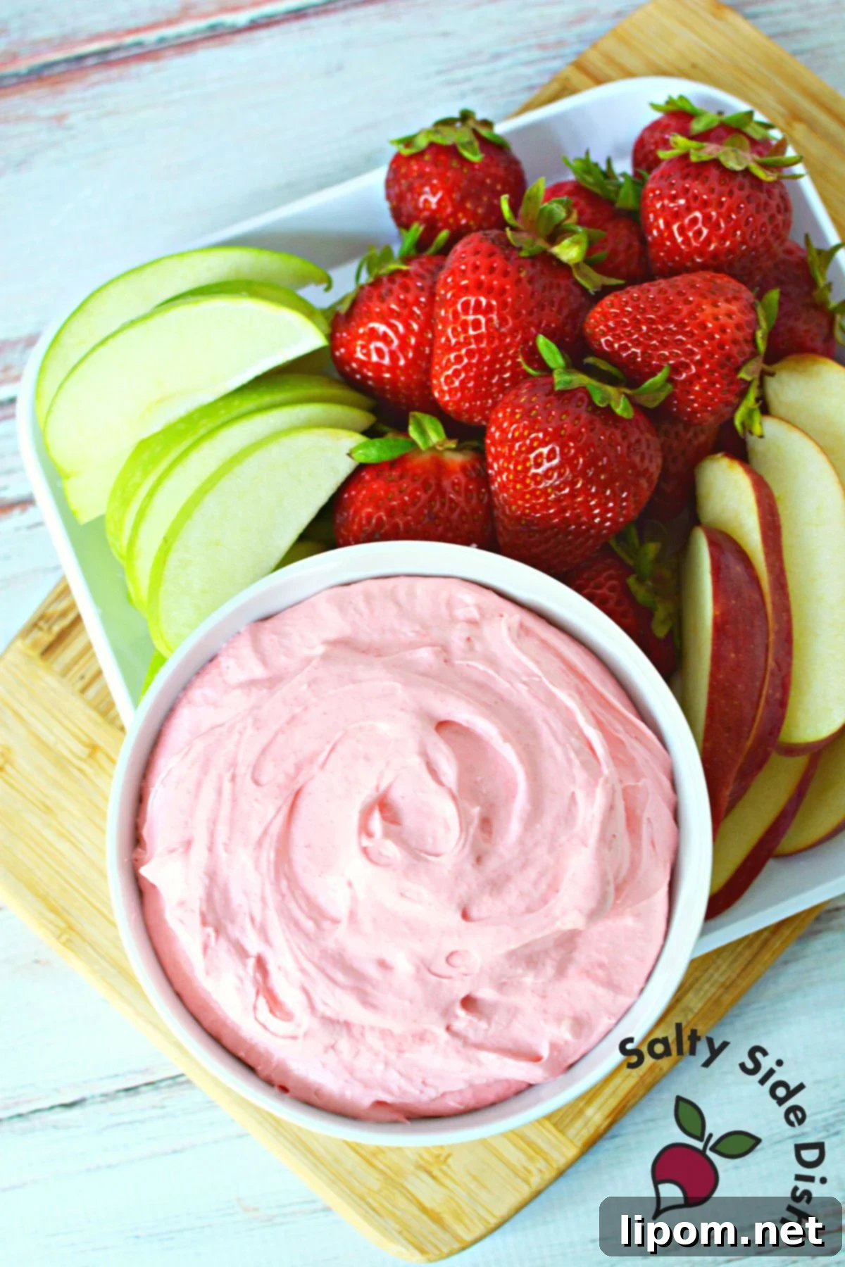 Luscious Strawberry Dip 5 A large, inviting bowl of creamy strawberry fruit dip, surrounded by an array of colorful fresh fruits and cookies, perfect as an easy and delicious party appetizer for a crowd.