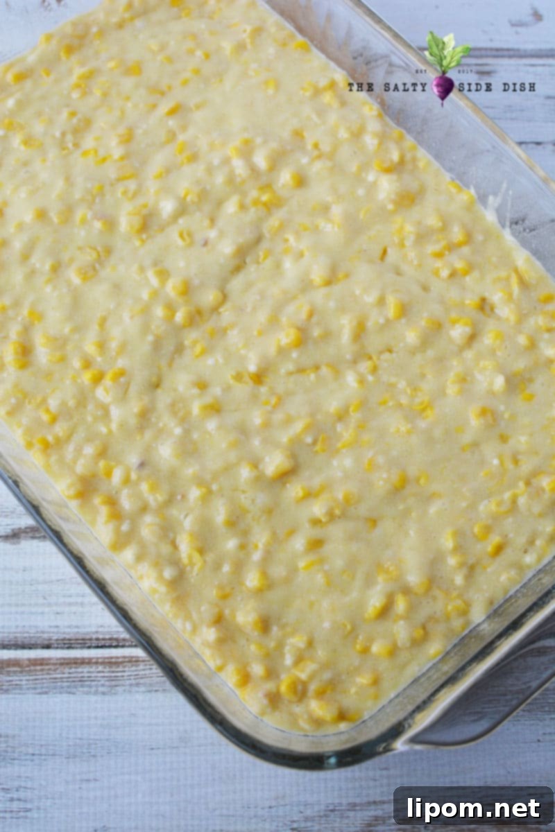 Creamy corn casserole mixture poured into a 9x13 baking dish, ready for the next layer.