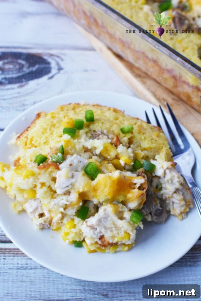 A serving of Mexican corn casserole with chicken on a plate, garnished with fresh toppings like creamy corn and mushrooms.