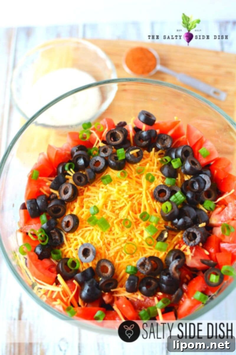 Fiesta Taco Stack 6 A finished 7-layer taco salad, ready to be served, with serving tongs.