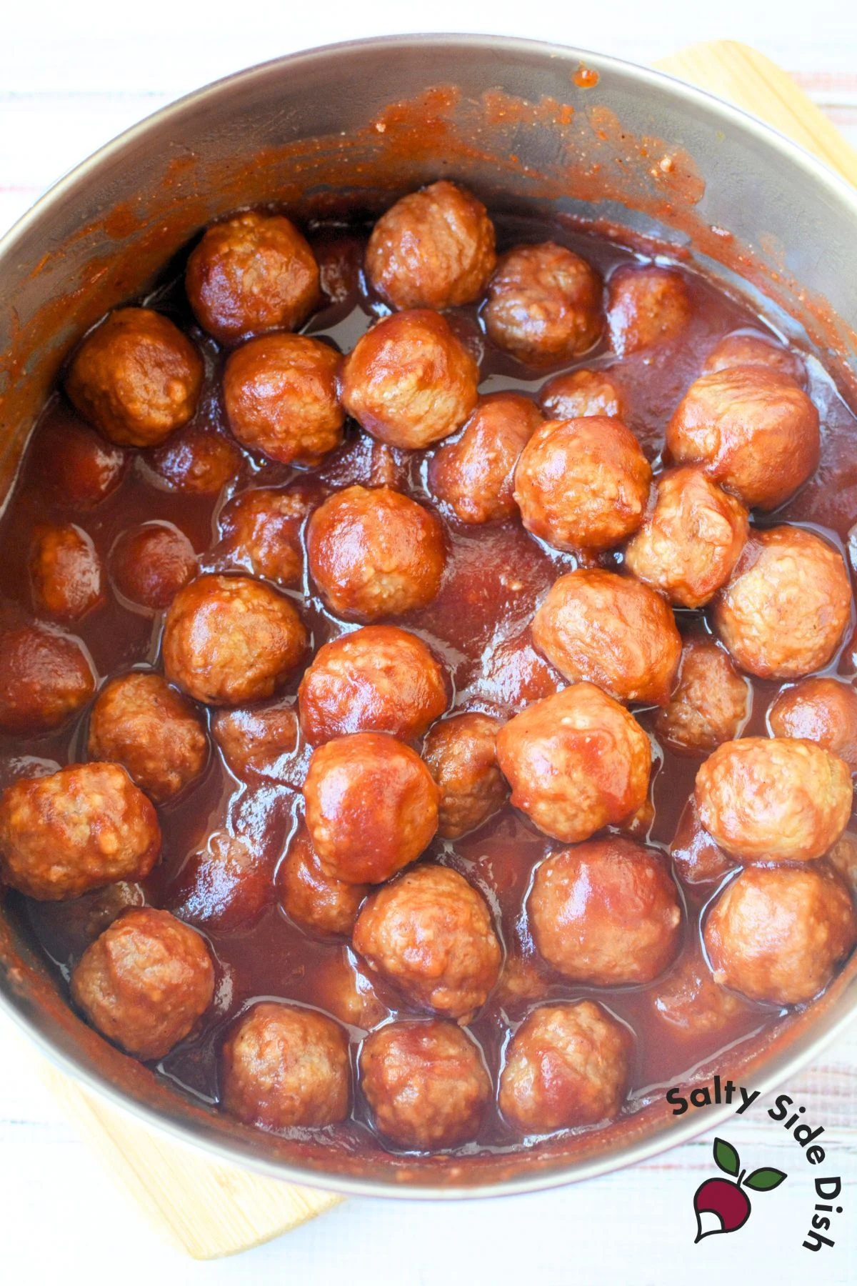 stovetop pot of meatballs in cranberry chili sauce simmering in glaze