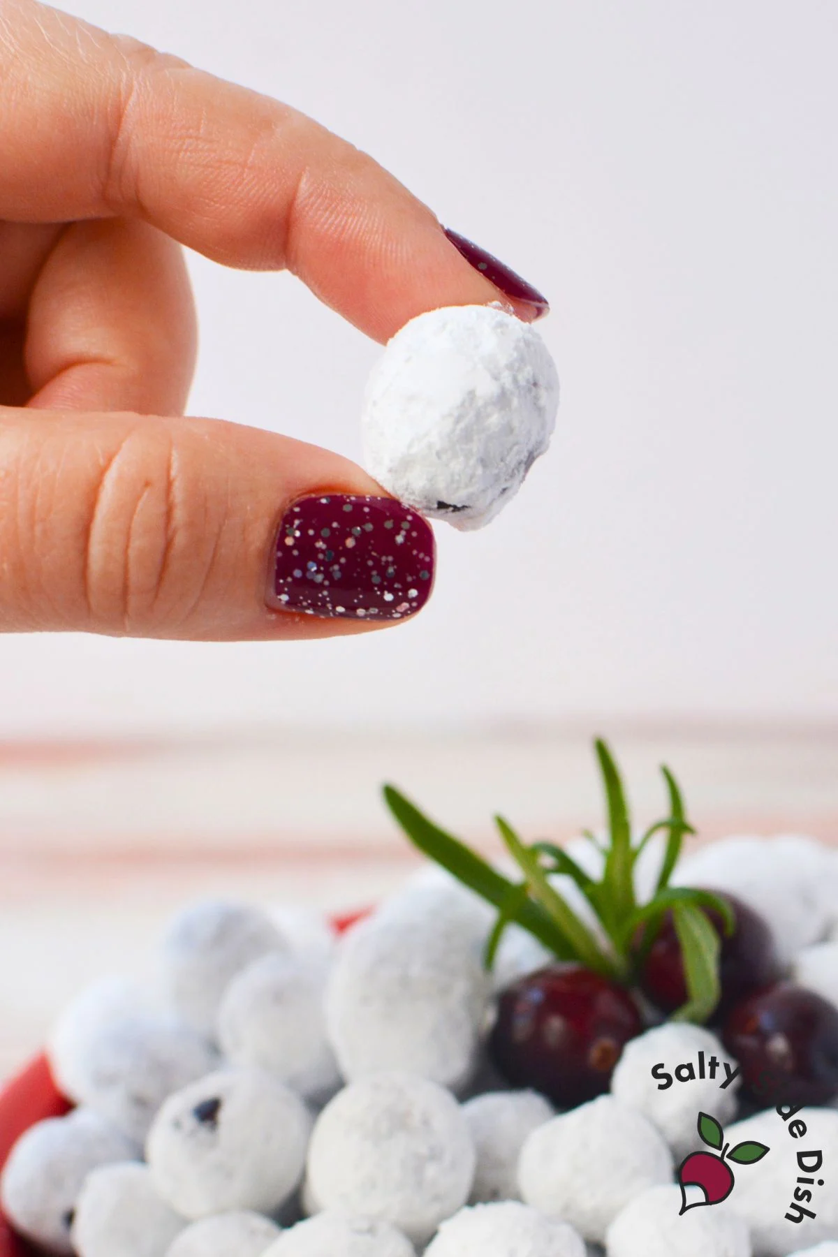 Close up of a homemade sugared cranberry coated in powdered sugar, ready to enjoy.