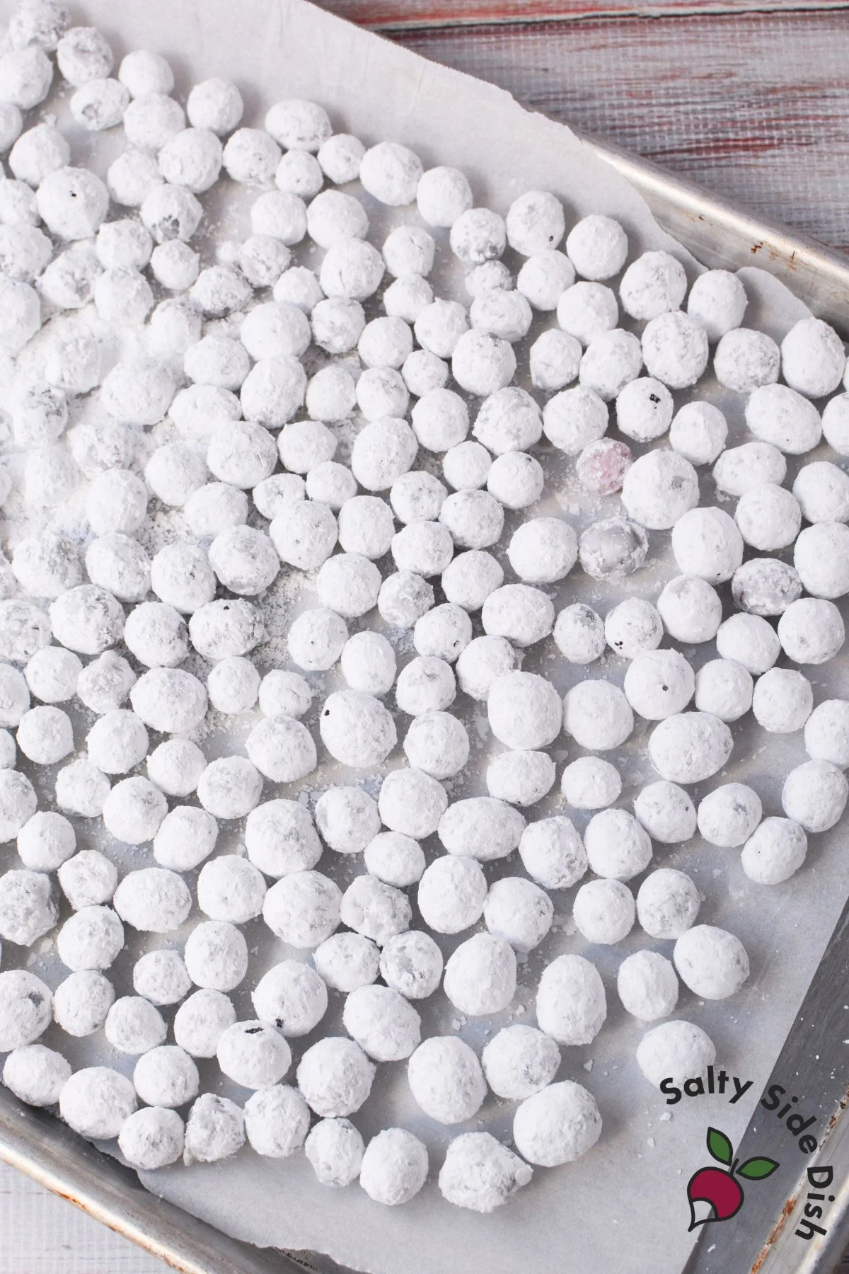 Tray of sugared cranberries coated in powdered sugar, cooling before serving as garnish or snack.