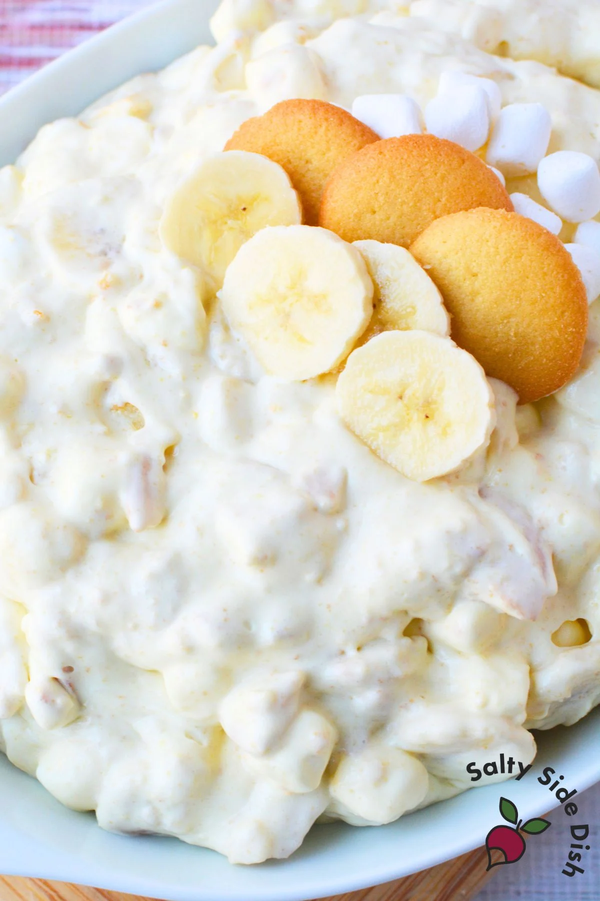 Creamy banana pudding fluff salad topped with sliced bananas, marshmallows, and crushed Nilla wafer cookies.