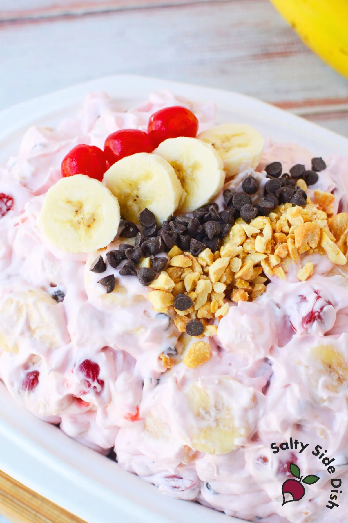 whipped topping sweetened condensed milk and cherry pie filling being combined for banana split fluff salad
