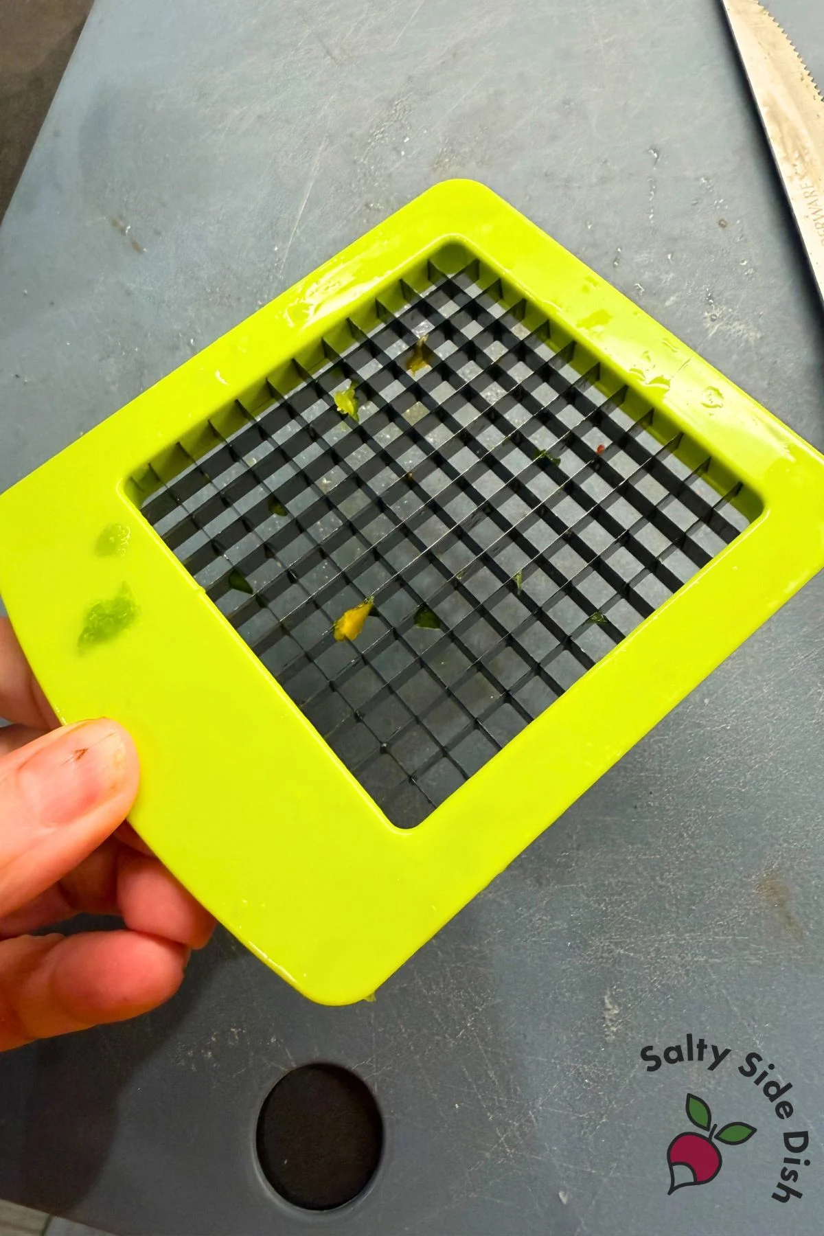 Hand holding vegetable dicer blade used to chop bell peppers into tiny pieces for rice bowl recipe