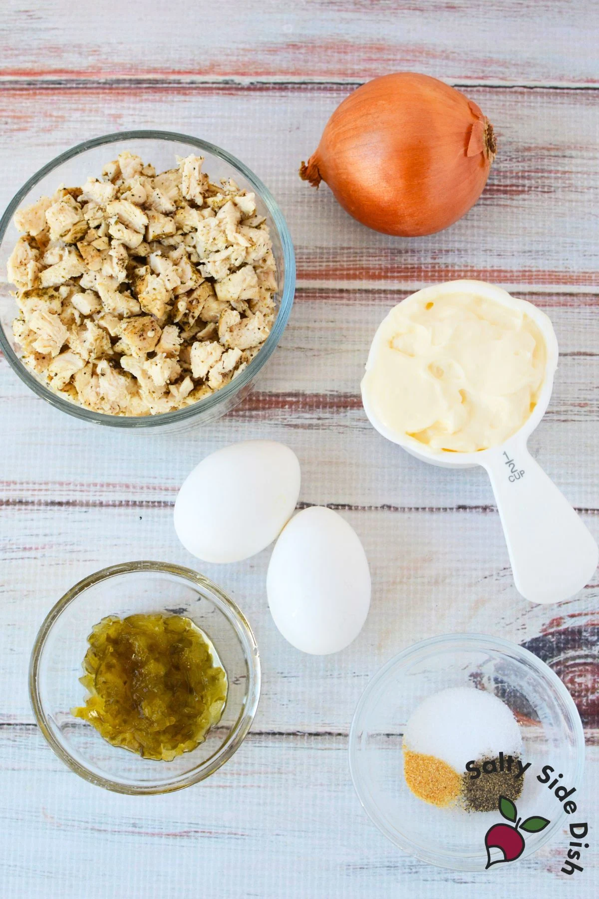 Ingredients for chicken salad including cooked chicken, onion, eggs, mayo, relish, and seasonings.