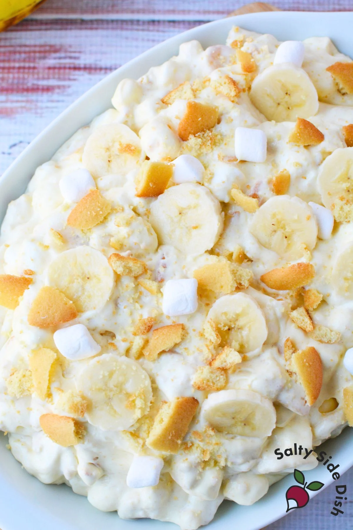 Large serving bowl of banana pudding fluff dessert salad with marshmallows and Nilla wafer cookie pieces.