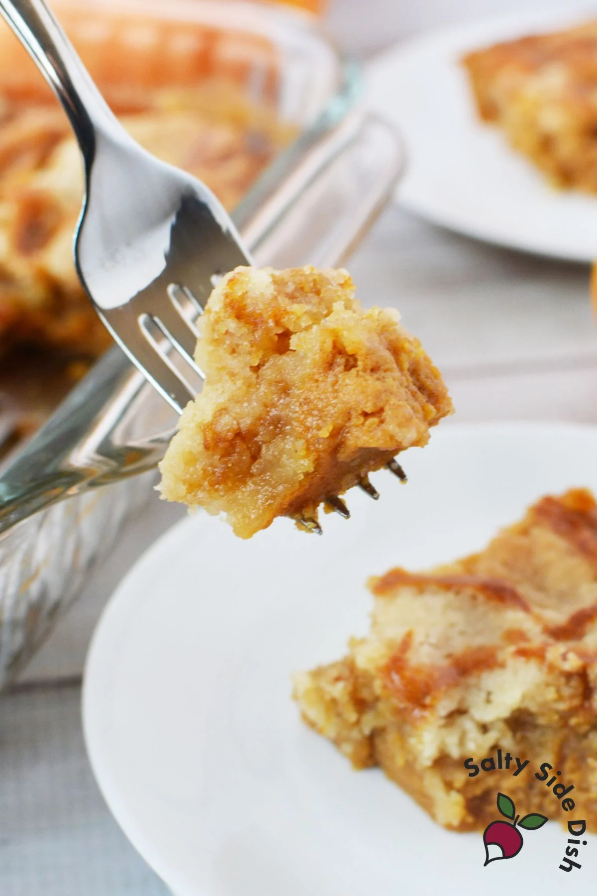 Close-up forkful of gooey pumpkin dessert showing moist pumpkin layer and rich buttery topping