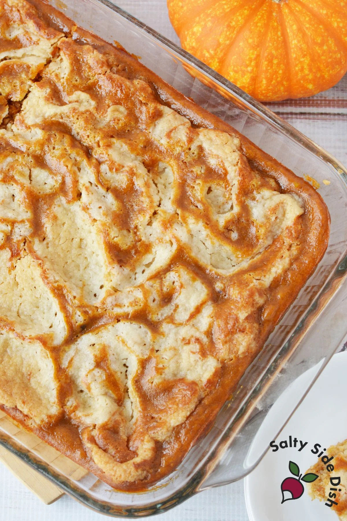 Baking dish of pumpkin pie butter cake with golden brown top cut into squares ready to serve