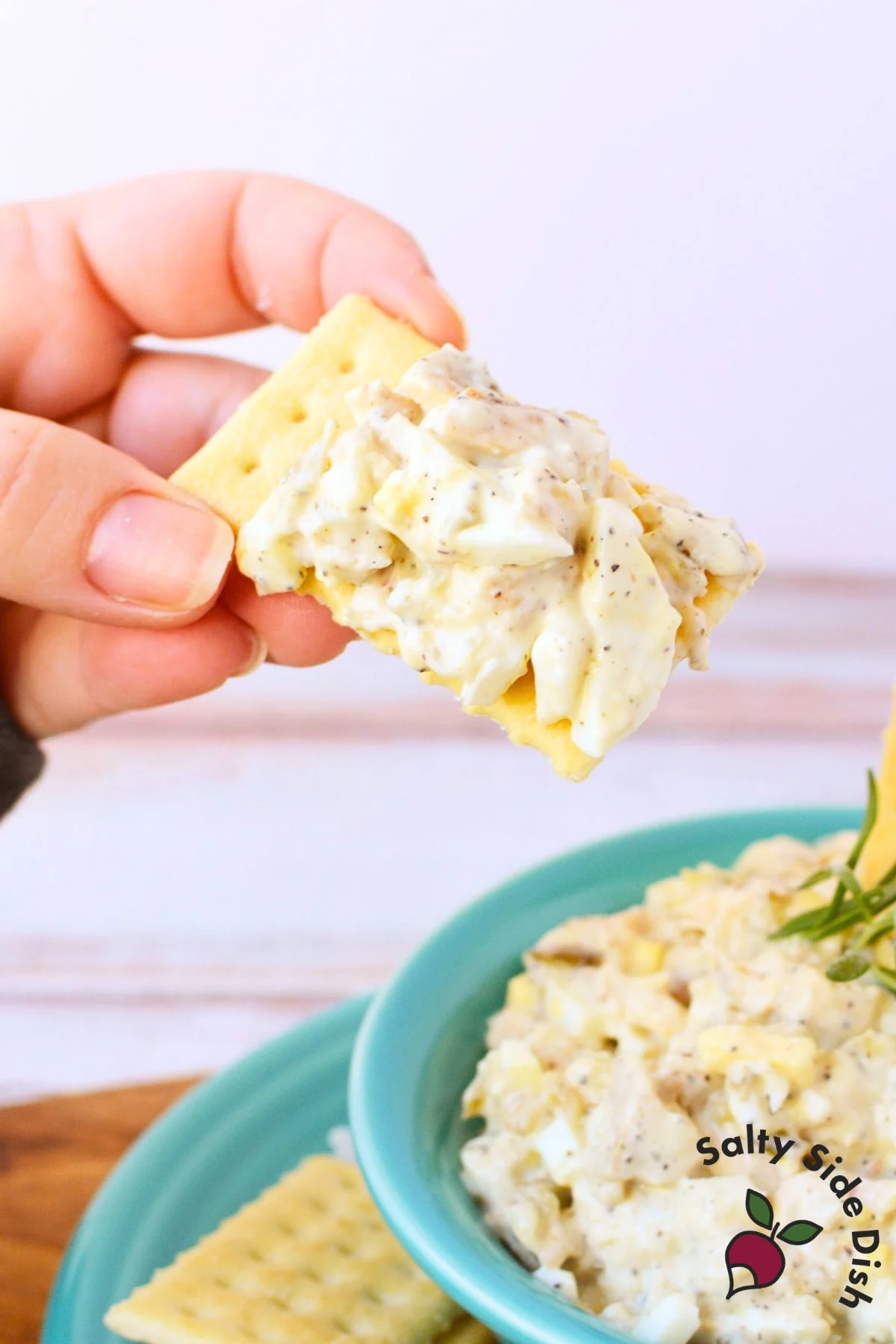 Scooping creamy chicken salad onto a cracker for an easy football party bite.