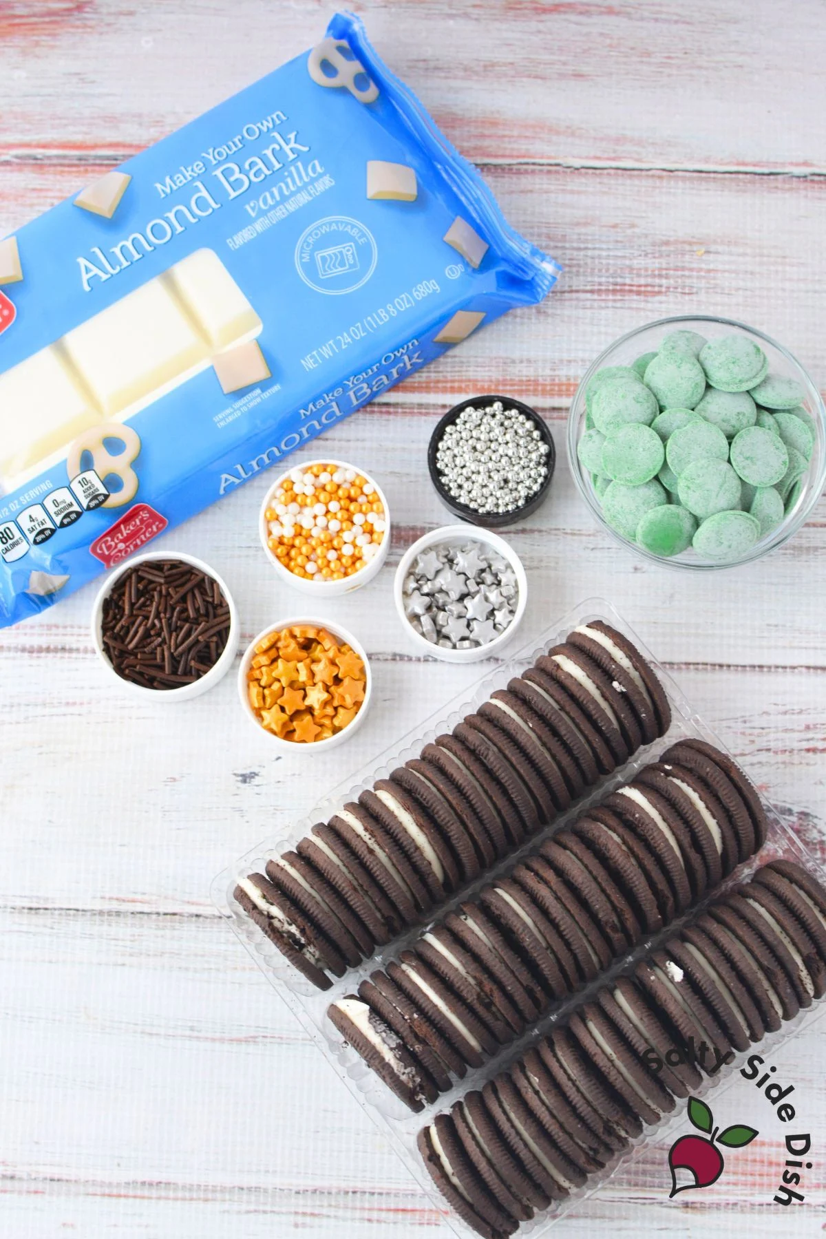 ingredients for chocolate covered christmas oreos including vanilla almond bark oreo cookies candy melts and holiday sprinkles