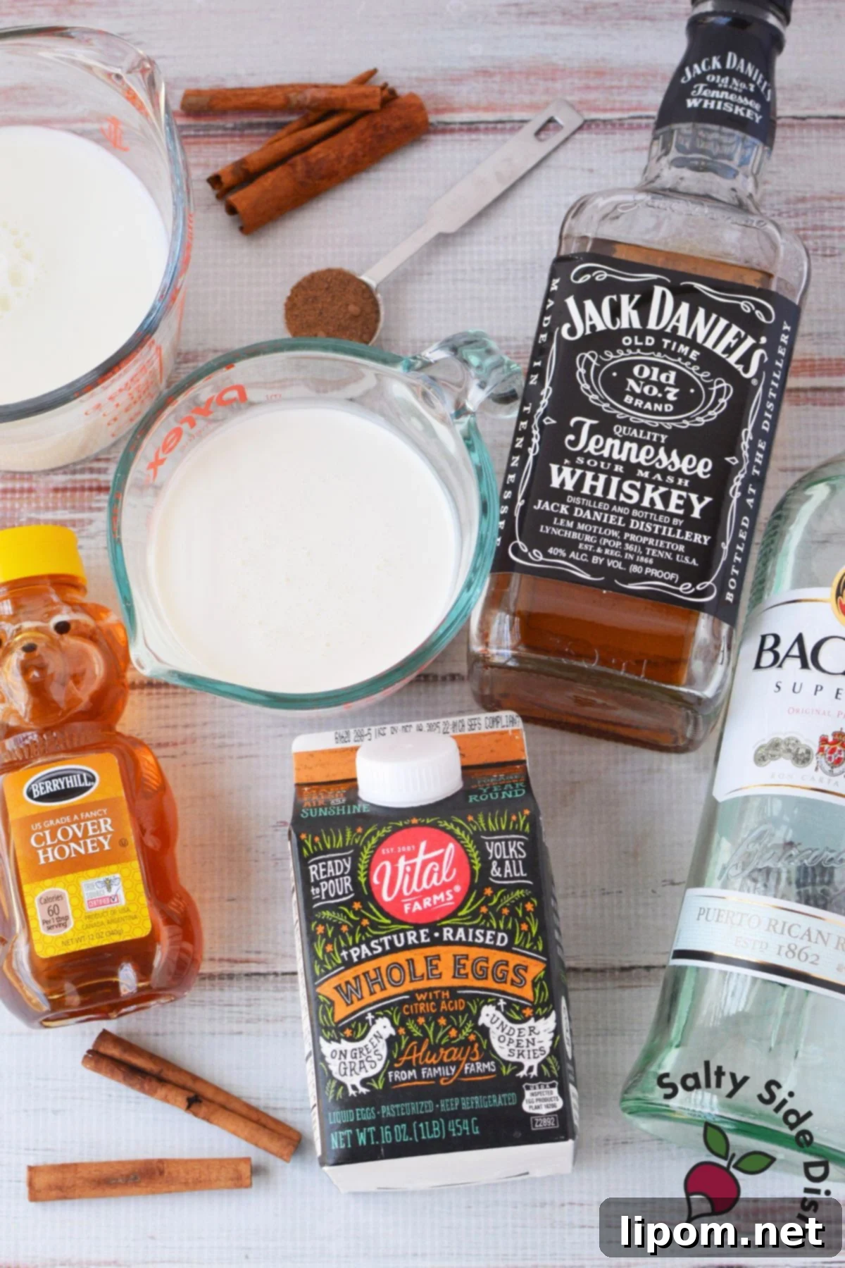 Spiked Holiday Cheer 3 A vibrant display of spiked eggnog ingredients, including pasteurized whole eggs, creamy milk, rich cream, golden honey, smooth bourbon, aromatic rum, and freshly ground nutmeg.
