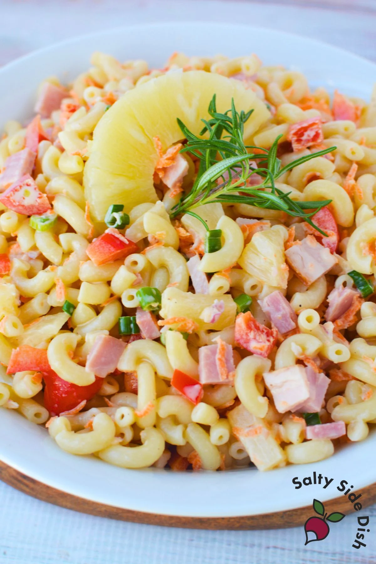 Hawaiian pasta salad served in a white bowl with elbow macaroni diced ham pineapple and vegetables