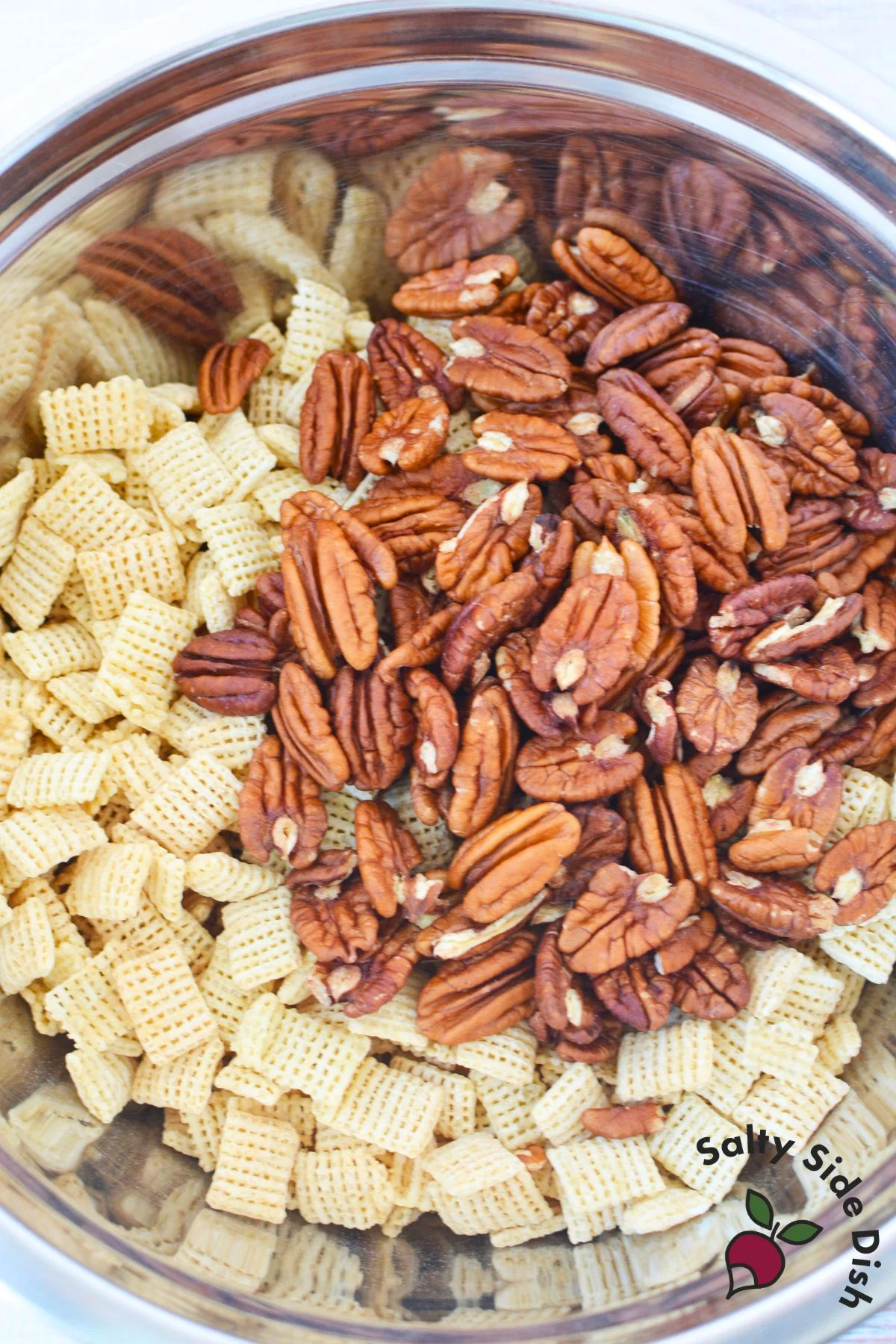 Rice cereal and pecan halves combined in a bowl before adding caramel