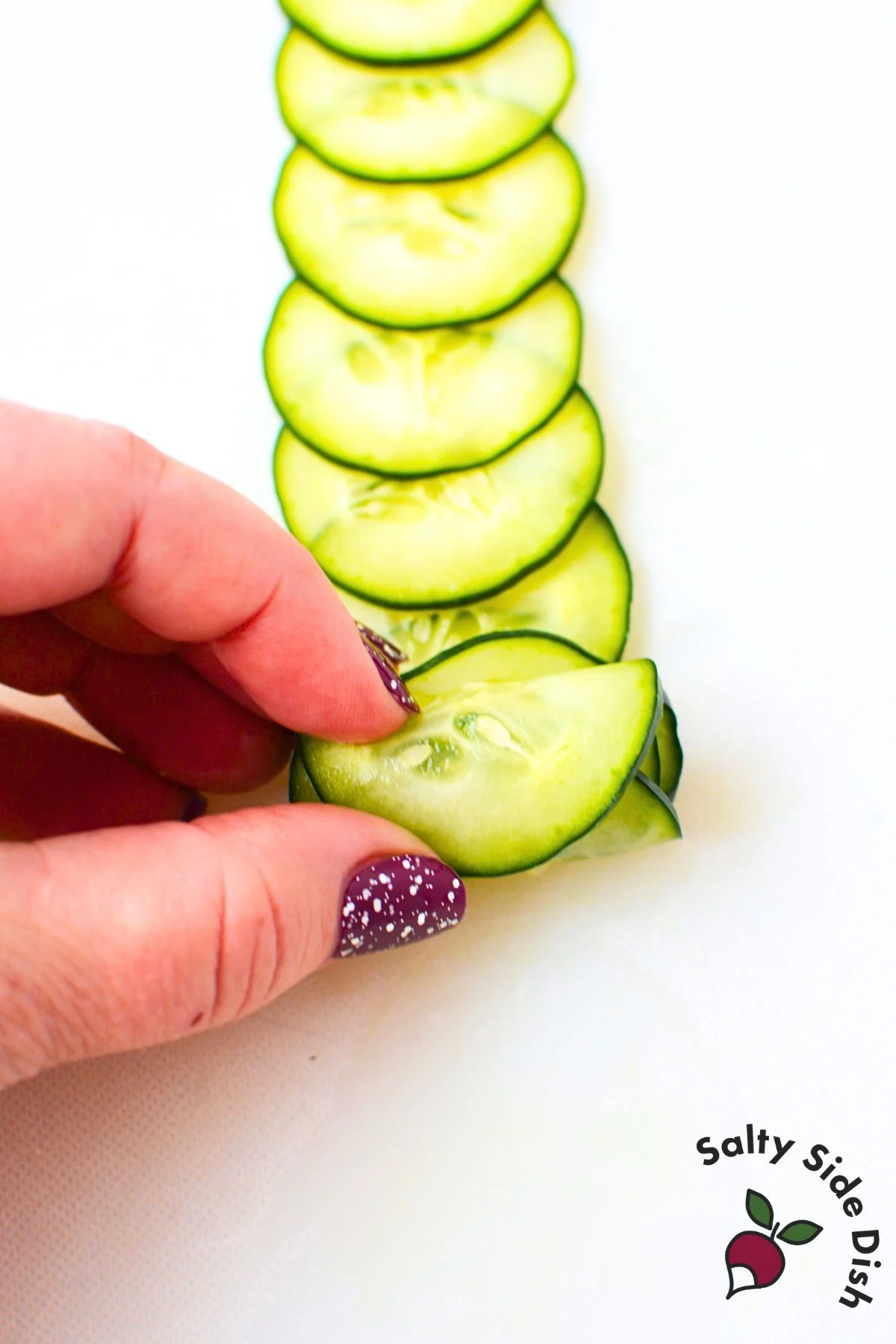 Rolling thin cucumber slices together to form a cucumber rose garnish