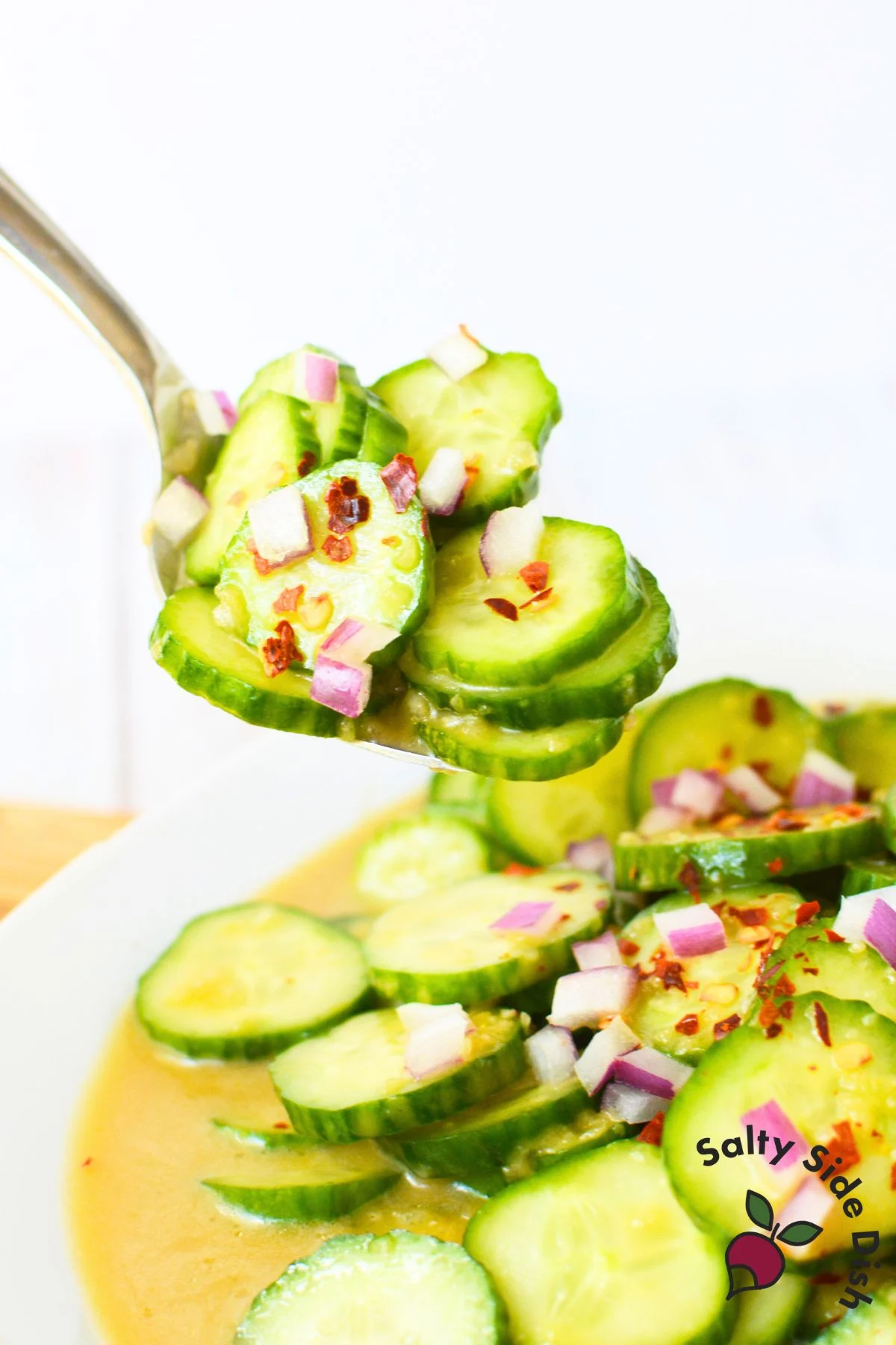 Spoonful of balsamic cucumber salad showing thin sliced cucumbers coated in honey balsamic dressing