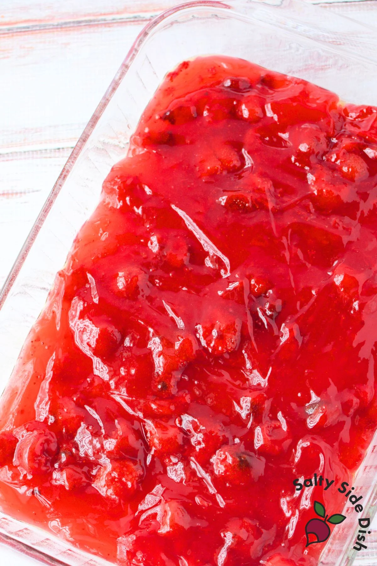 Strawberry pie filling spread evenly in the bottom of a greased 9x13 glass baking dish for strawberry lemon dump cake
