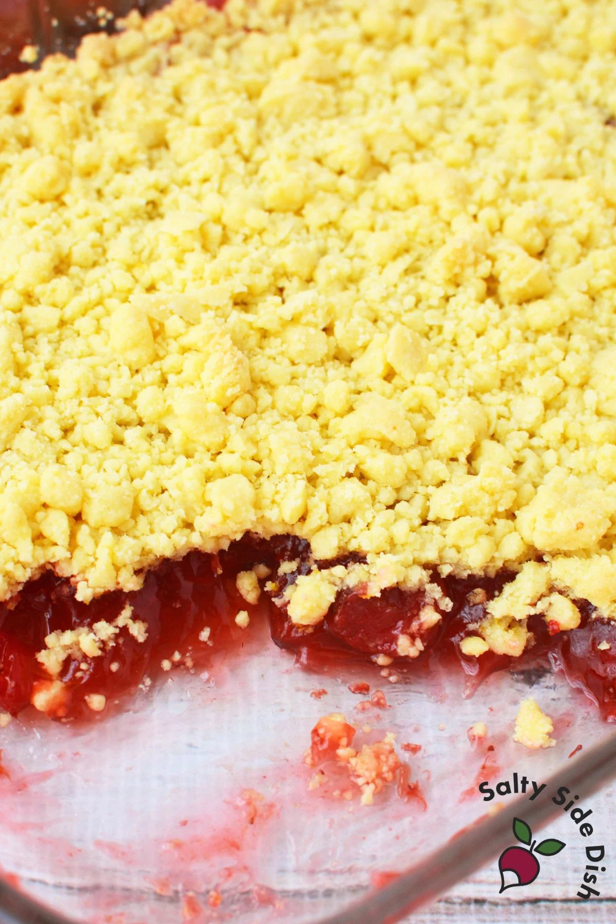 Unbaked strawberry lemon dump cake in a glass casserole dish showing the lemon cake mix crumb topping layered over strawberry pie filling
