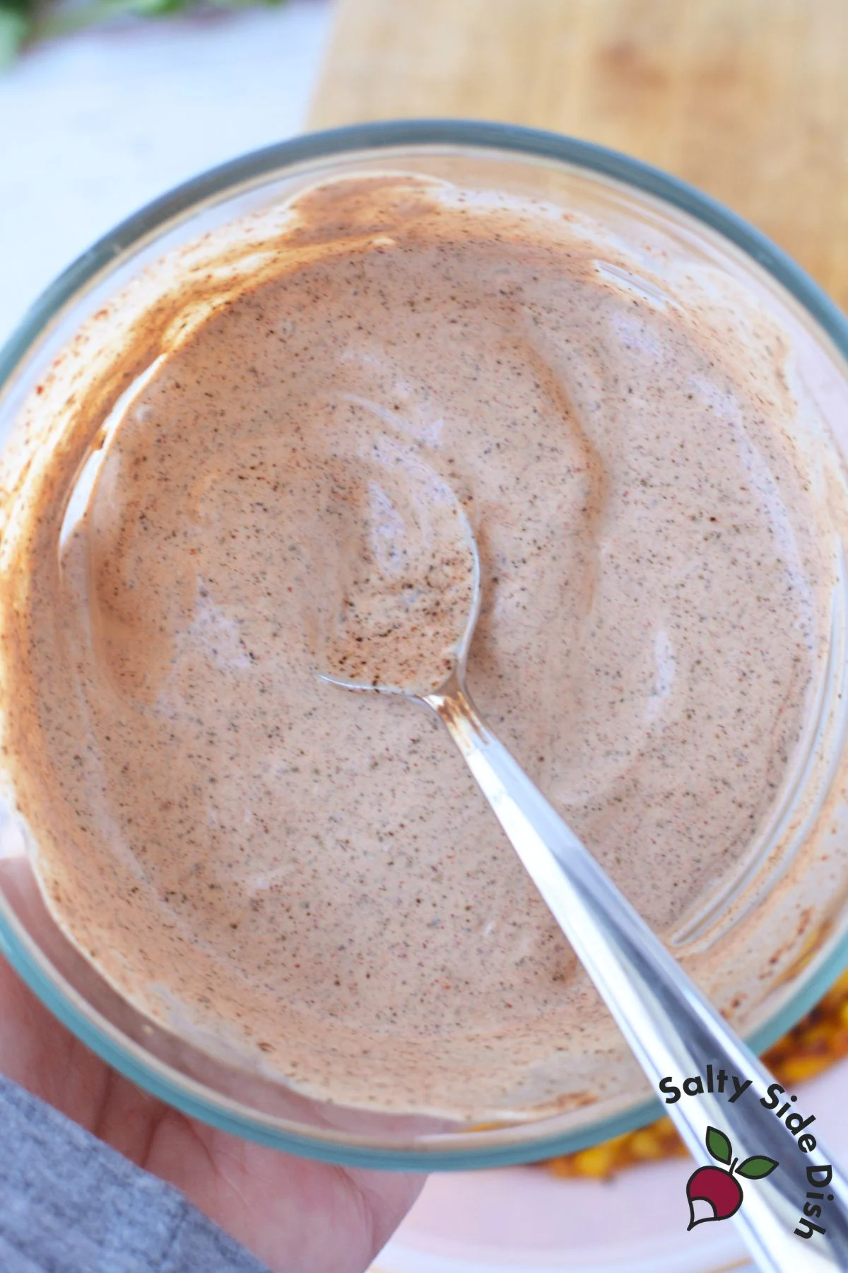 Creamy elote sauce made with sour cream, mayonnaise, lime juice, and chili powder in a glass bowl