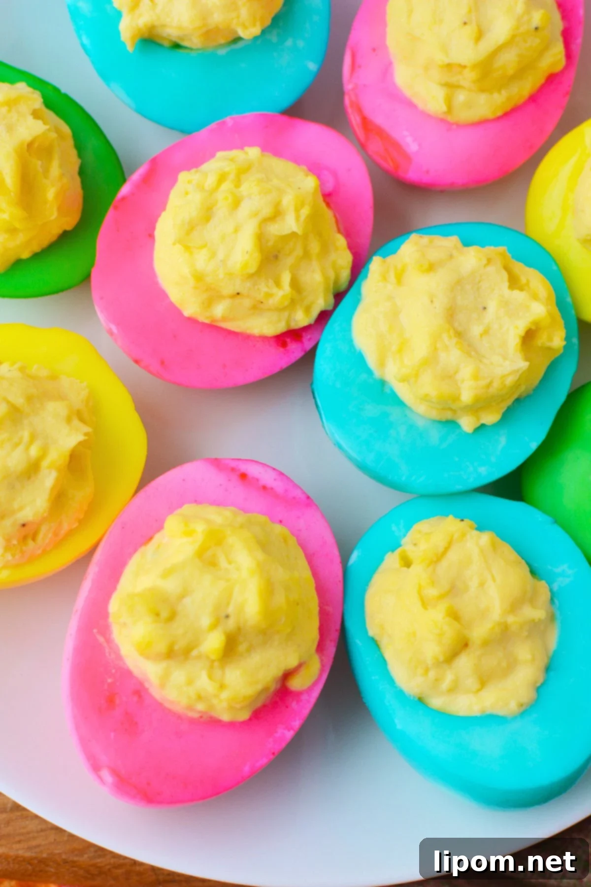 Finished colored deviled eggs with bright pink, yellow, and green egg whites on a serving tray