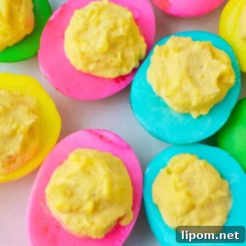 Finished colored deviled eggs with bright pink yellow and green egg whites on a serving tray