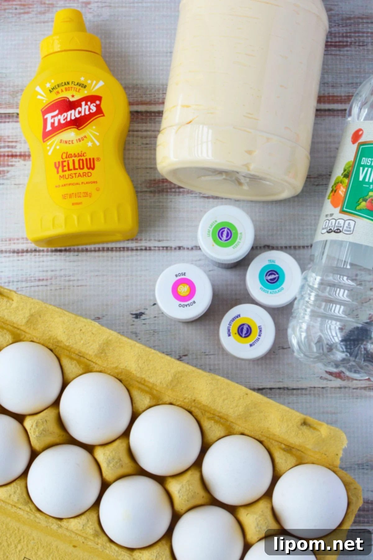 Ingredients for colored deviled eggs including eggs, mayonnaise, mustard, vinegar, and gel food coloring