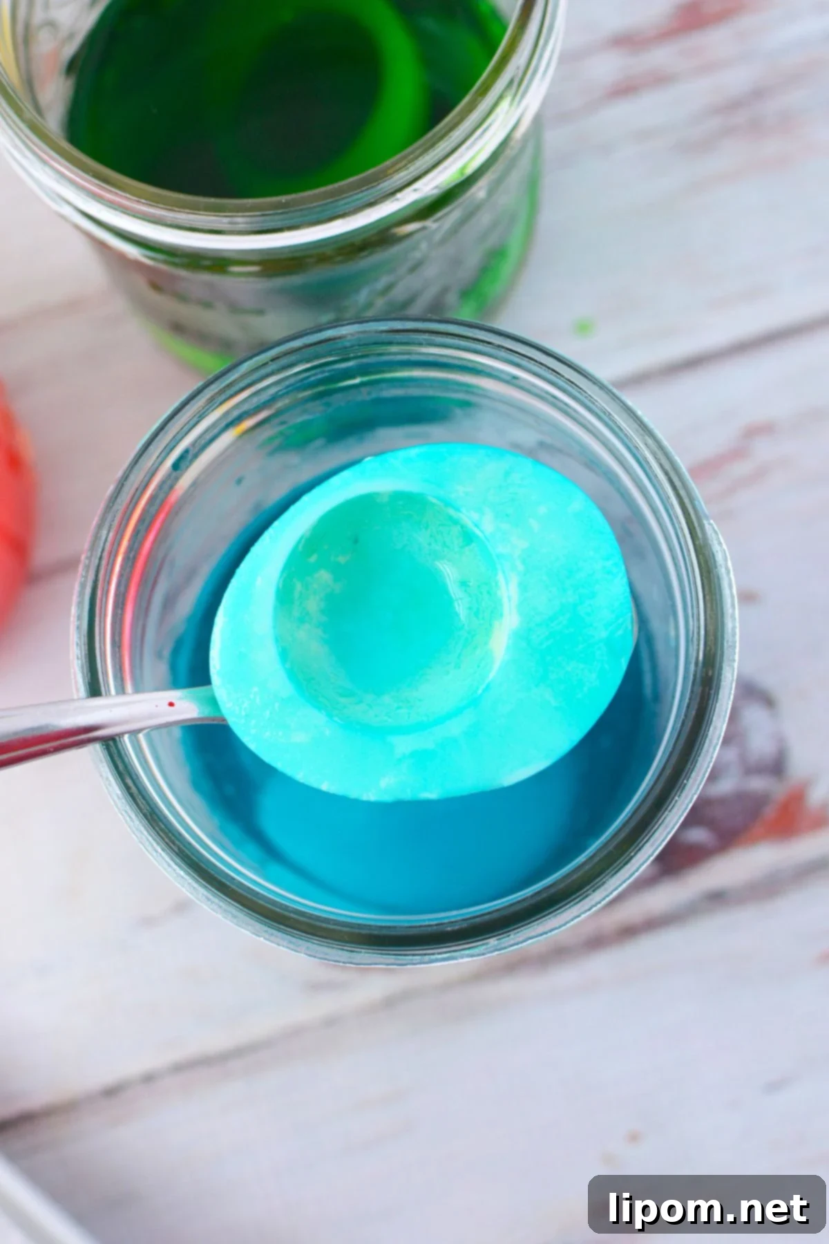 Egg white half being dyed blue in food coloring water for colored deviled eggs
