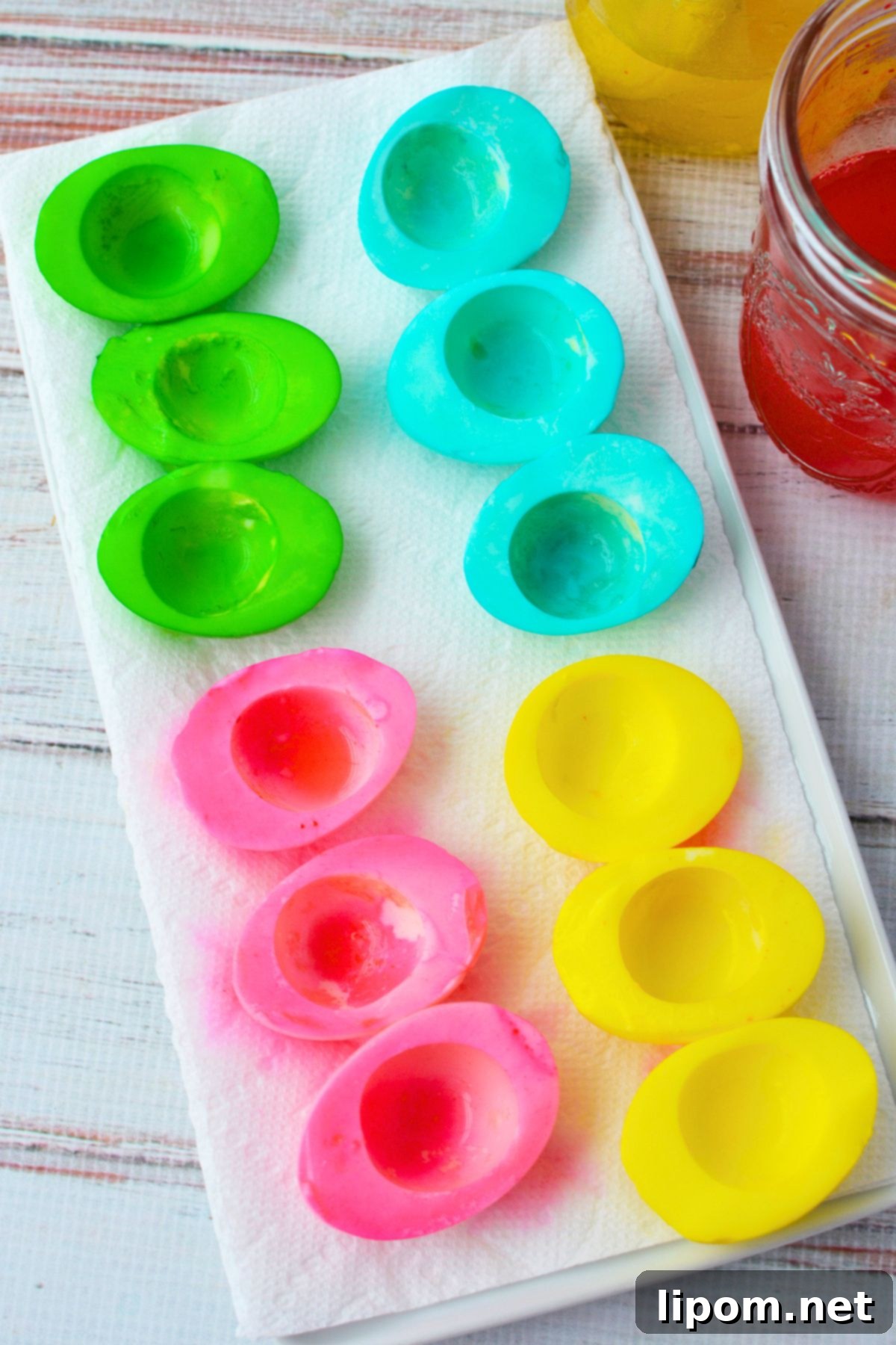 Dyed egg white halves in pink, yellow, blue, and green drying on paper towels for colored deviled eggs