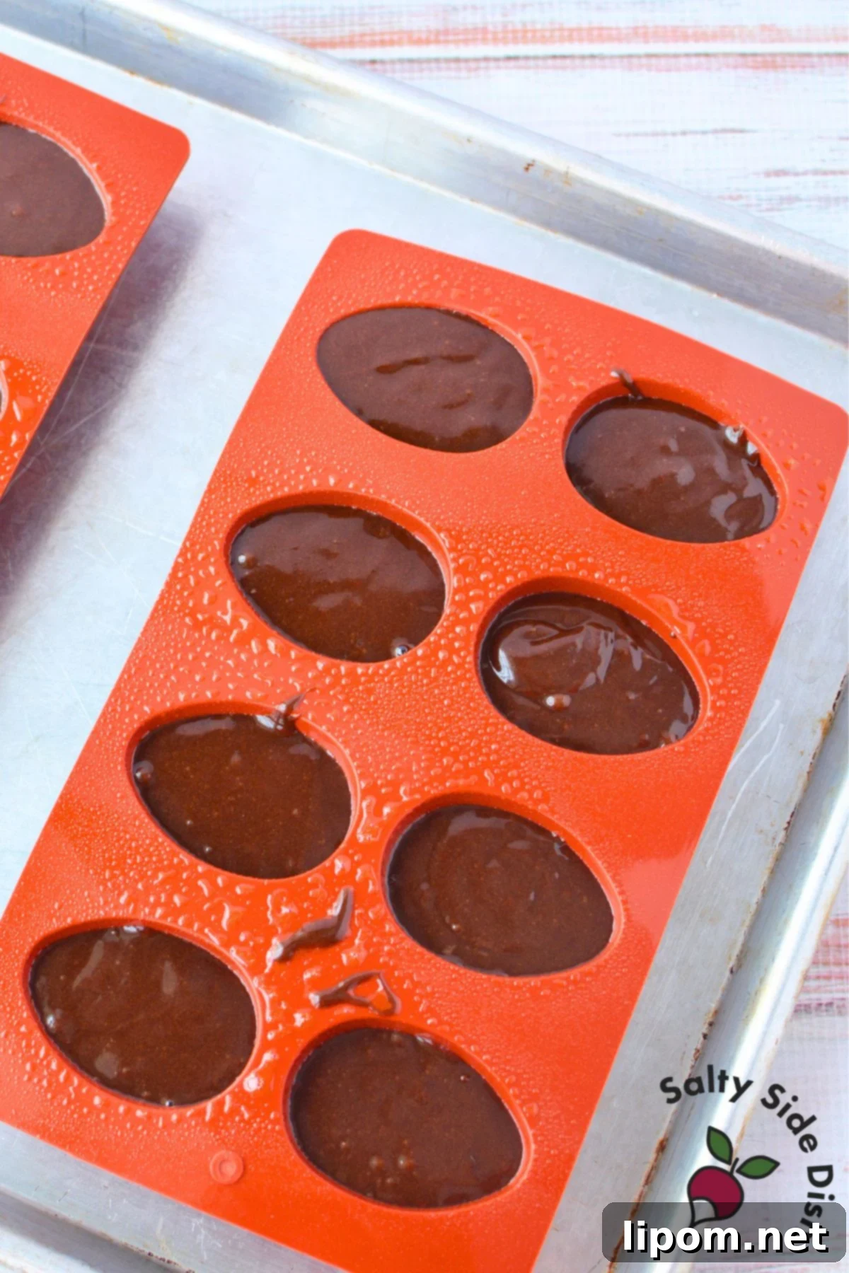 Chocolate brownie batter poured into silicone egg-shaped molds before baking