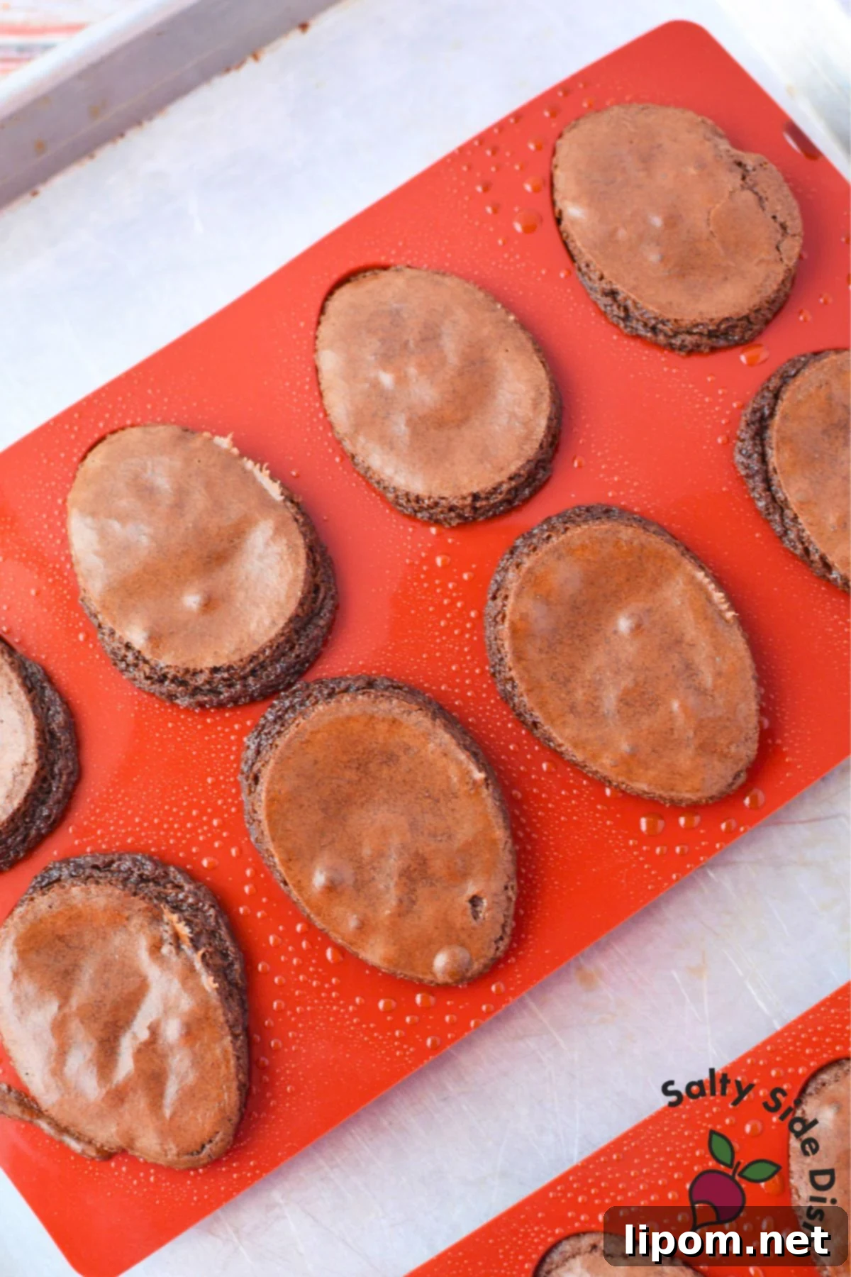 Freshly baked deviled brownies cooling in silicone egg molds on a baking sheet before filling