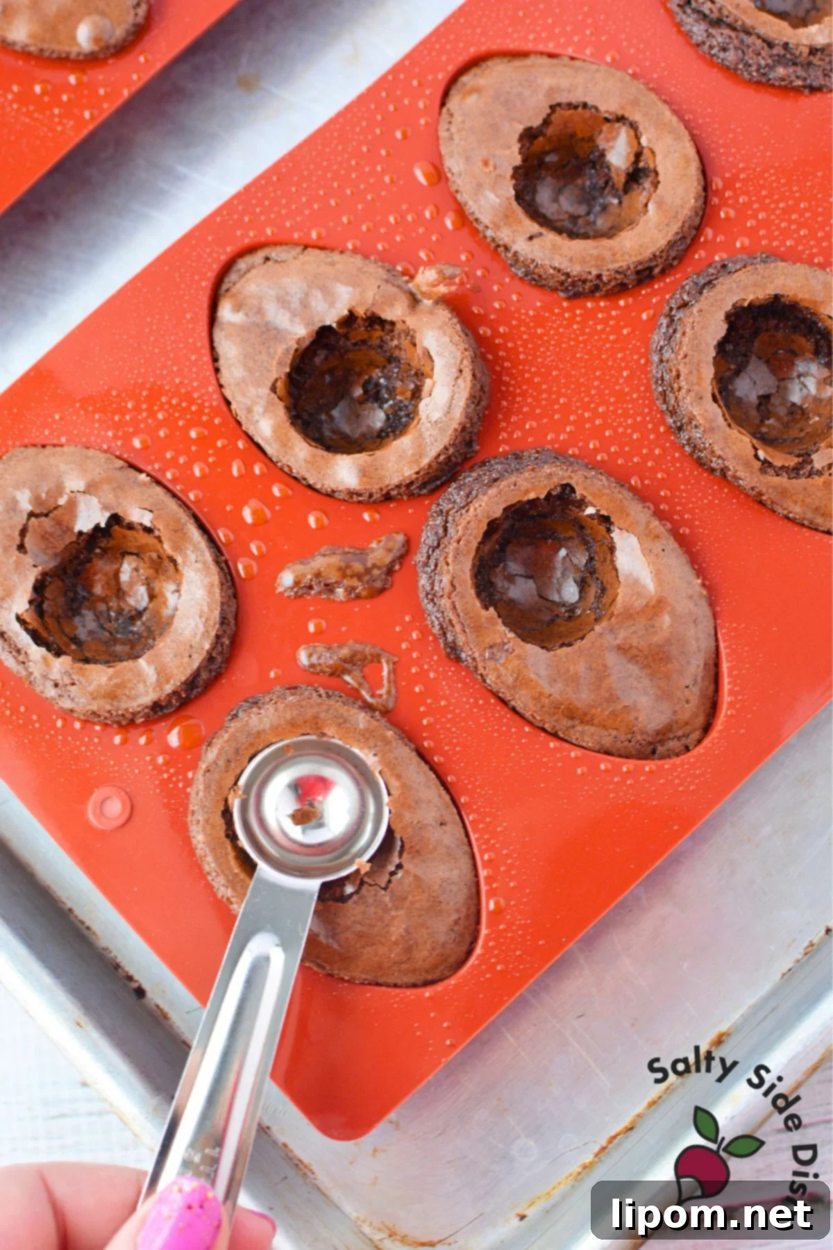 Removing baked brownie eggs from silicone molds using a spoon to create hollow centers