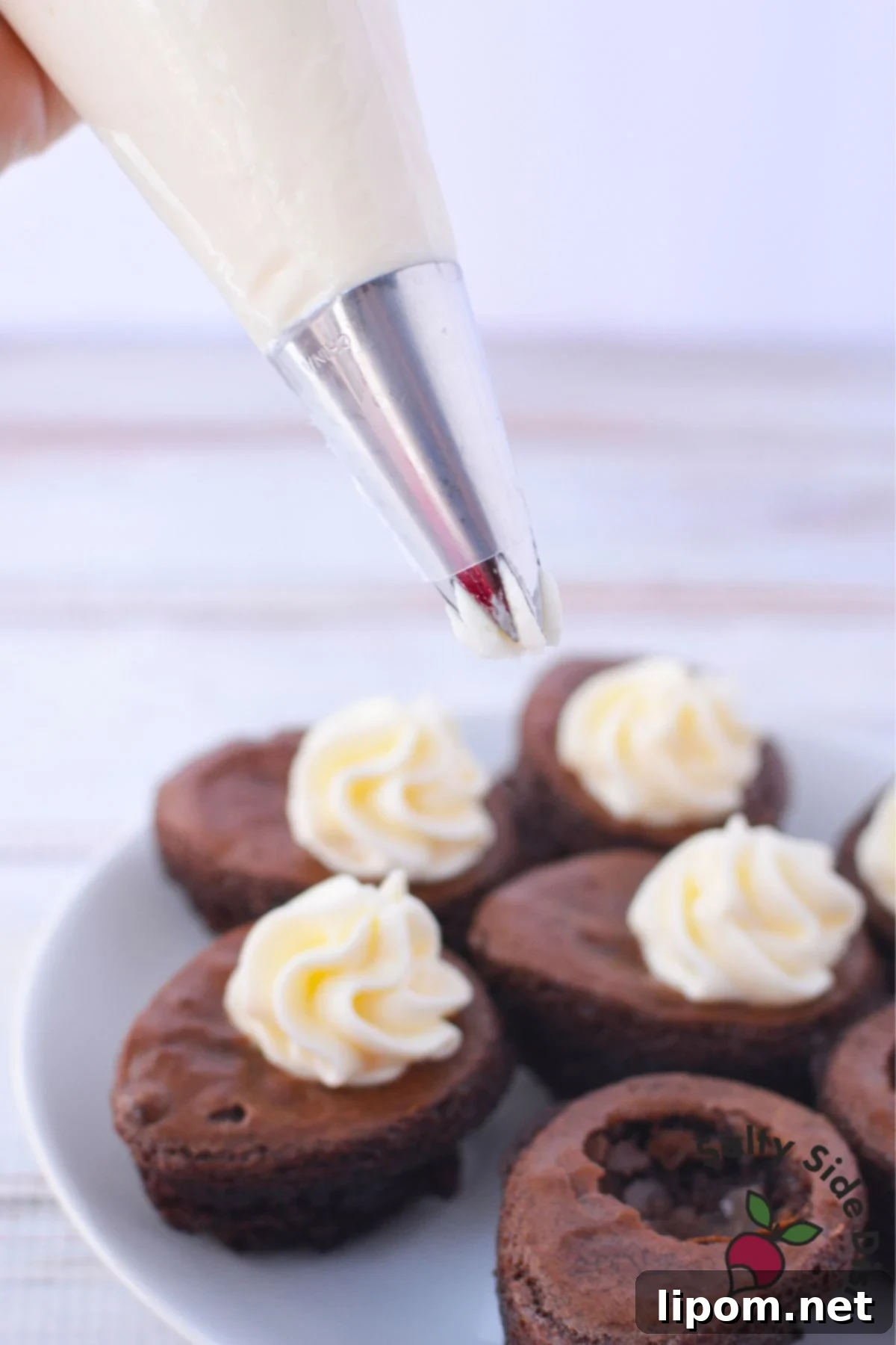 Piping cream cheese filling into hollowed brownie eggs using a pastry bag