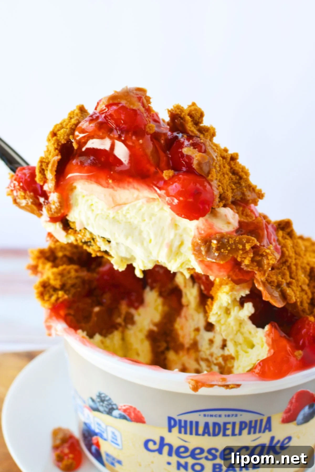 TikTok Japanese Cheesecake with Biscoff: A No-Bake Delight 2 Close up scoop of no-bake Biscoff cheesecake topped with cherry pie filling and crushed Biscoff cookies