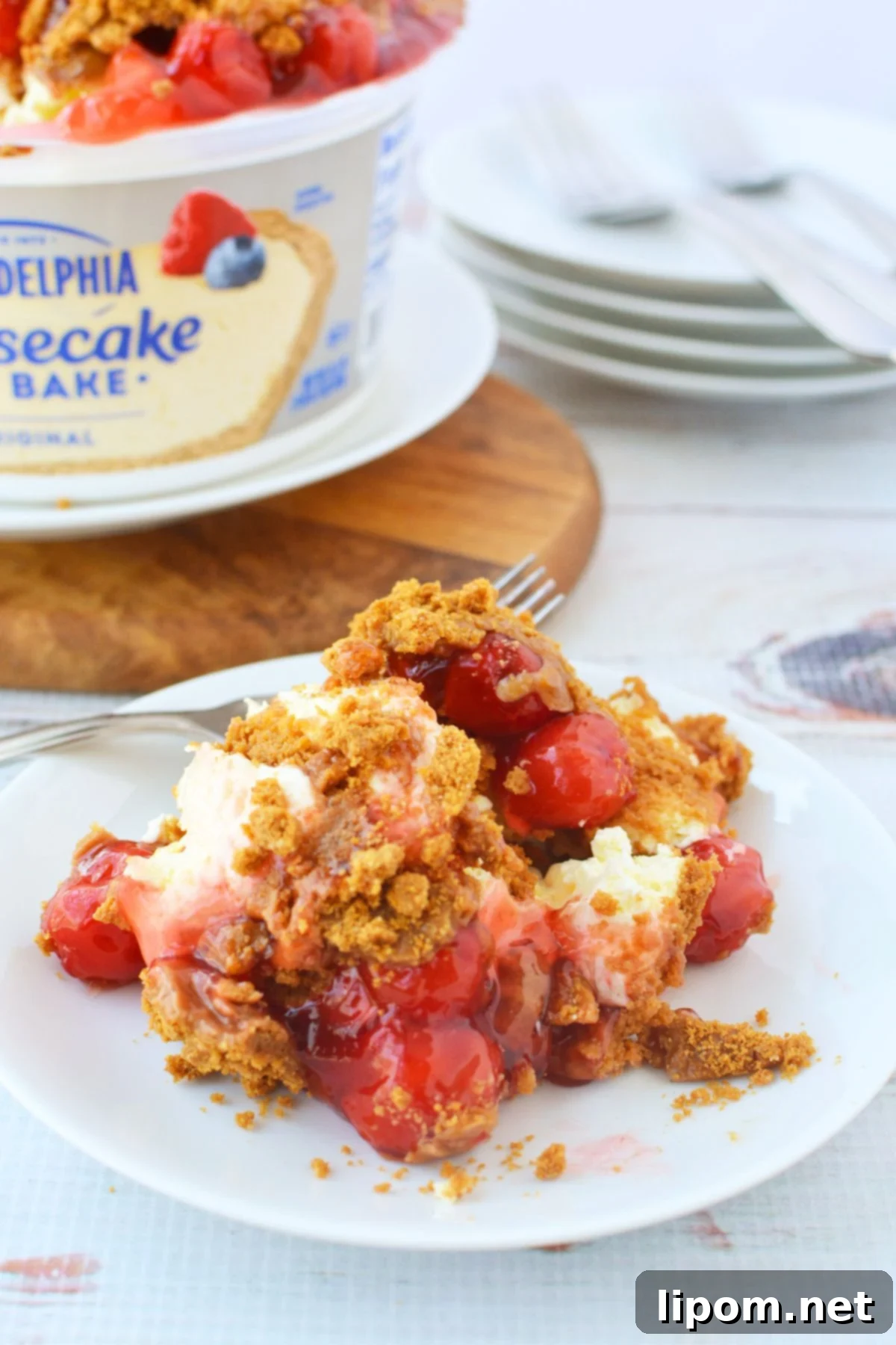 TikTok Japanese Cheesecake with Biscoff: A No-Bake Delight 11 Served slice of no-bake cheesecake with cherry topping and crushed Biscoff cookies on a white plate
