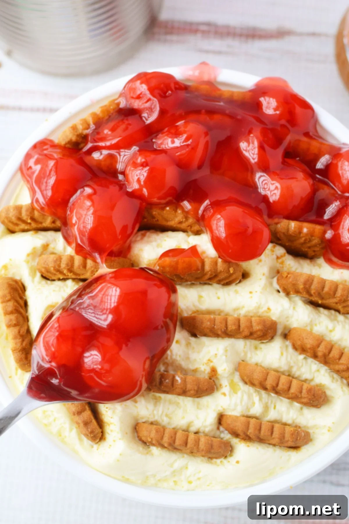 TikTok Japanese Cheesecake with Biscoff: A No-Bake Delight 6 Spoon pouring cherry pie filling over creamy no-bake cheesecake with Biscoff cookies