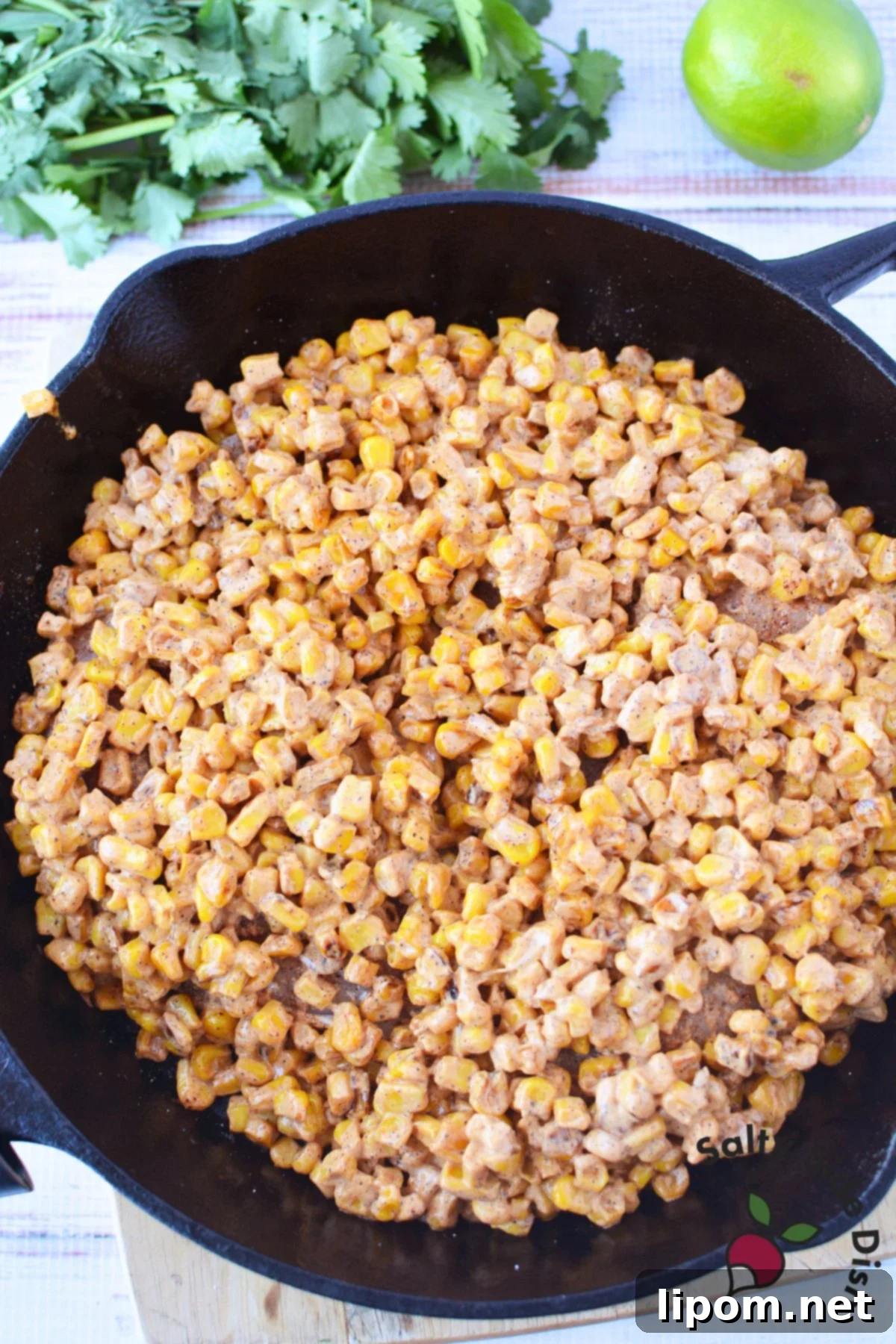 Mexican Street Corn Chicken Casserole 7 Charred corn mixed with creamy elote sauce in a cast iron skillet for street corn chicken bake