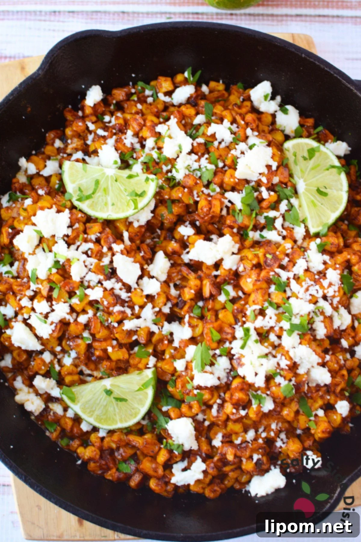 Mexican Street Corn Chicken Casserole 8 Mexican street corn chicken bake in a cast iron skillet topped with crumbled queso fresco, cilantro, and lime wedges