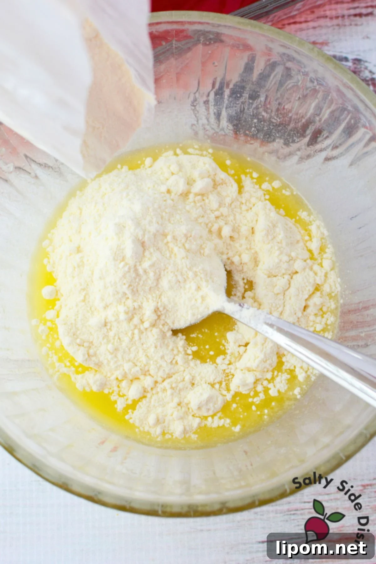 Strawberry Lemon Bliss Cake 7 Lemon cake mix and melted butter being combined in a glass bowl with a spoon to create a crumbly topping for the dump cake.
