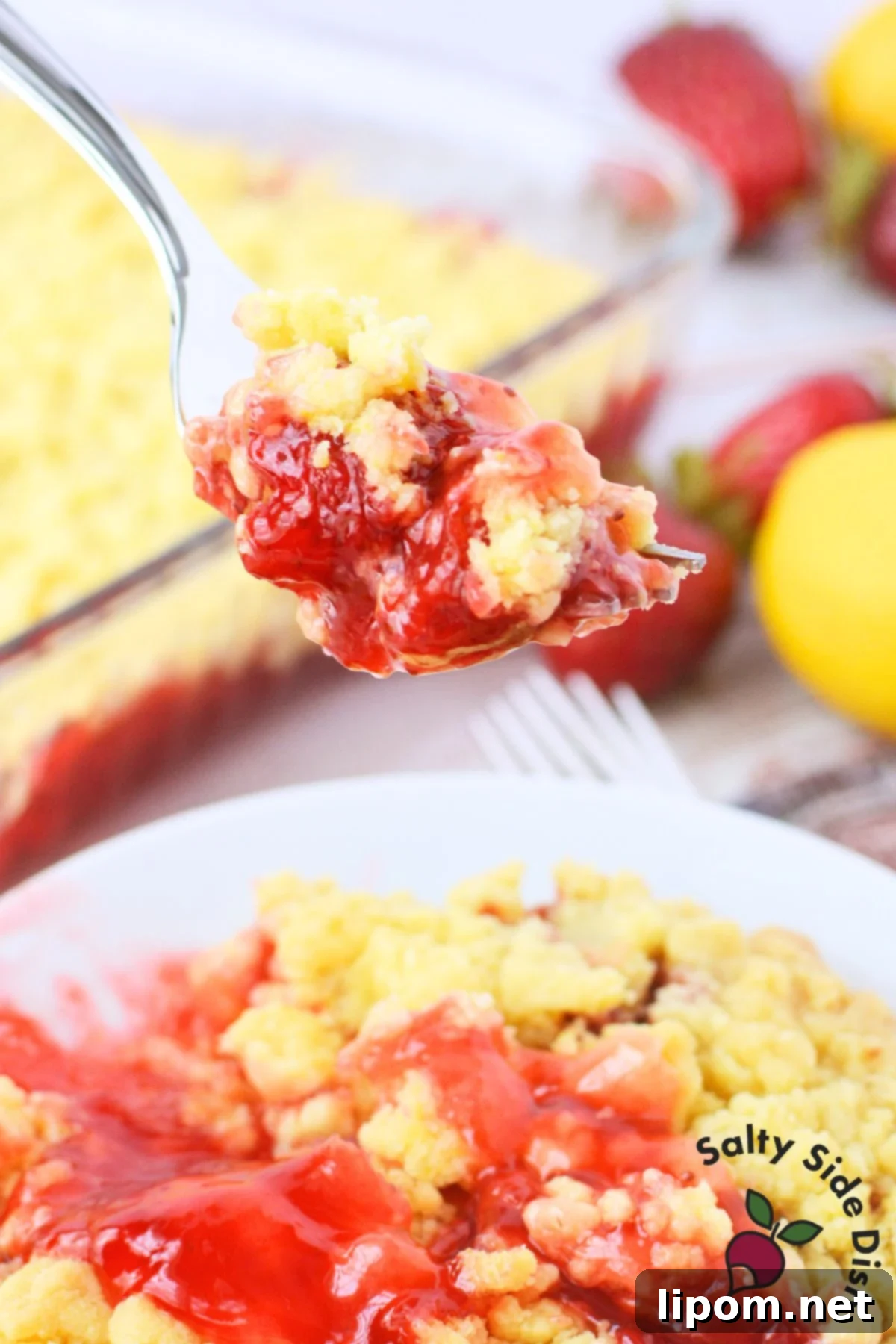 Strawberry Lemon Bliss Cake 10 A fork holding a bite of Strawberry Lemon Dump Cake, showcasing the gooey strawberry filling and golden lemon crumb topping.