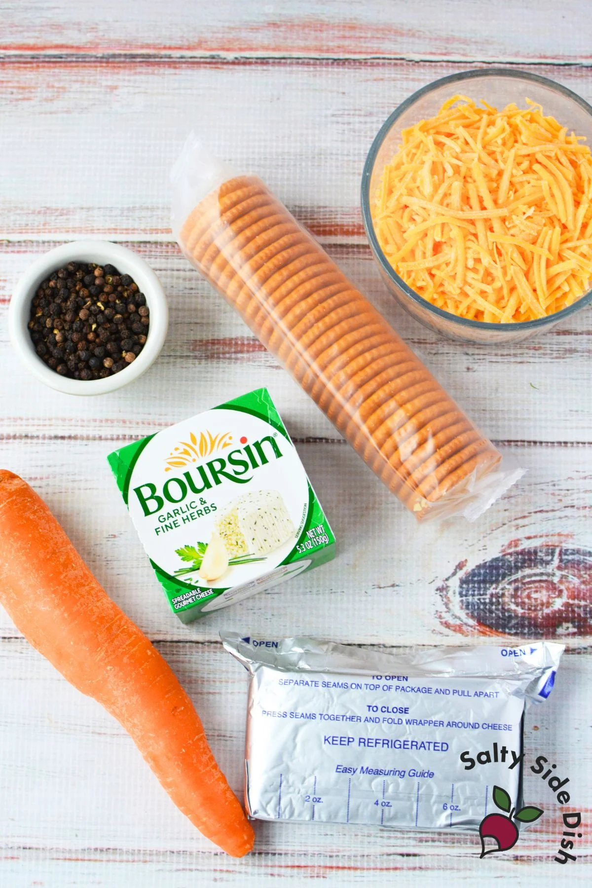 ingredients for mini chick cheeseball bites including Boursin garlic and herb cheese, cream cheese, shredded cheddar, carrot, peppercorns, and round butter crackers