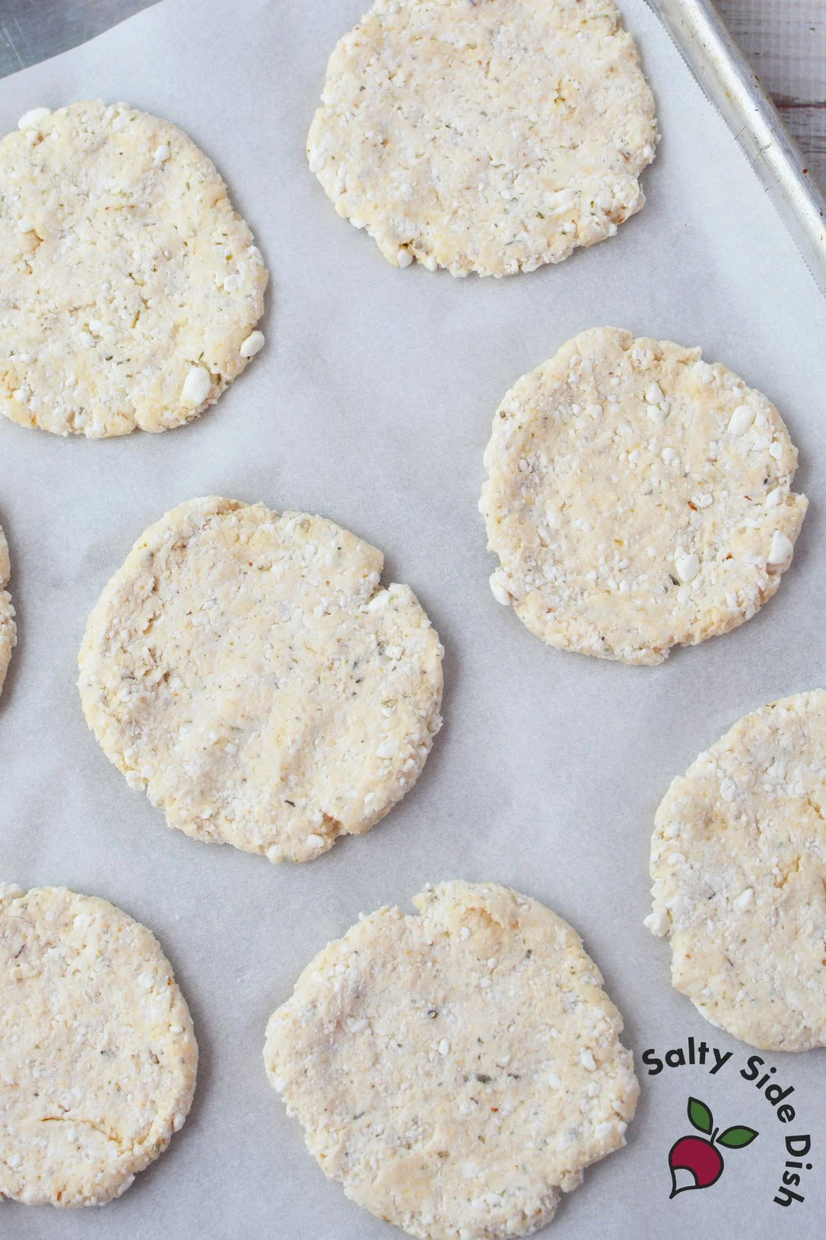eight unbaked cottage cheese pizza crusts shaped into rounds on a parchment lined baking sheet