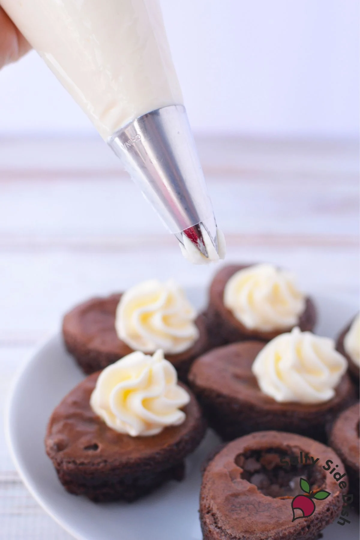 Piping cream cheese filling into hollowed brownie eggs using a pastry bag