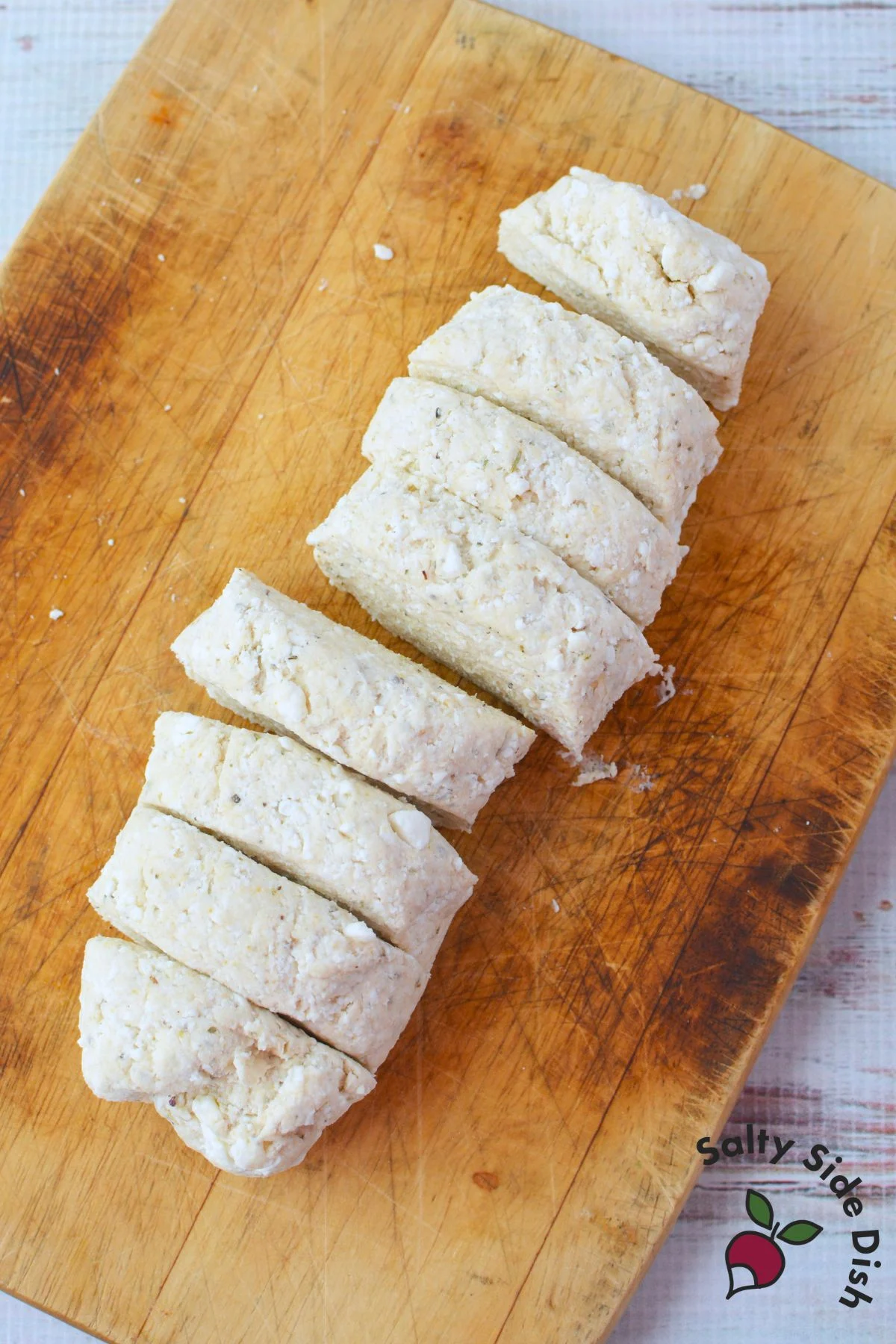 cottage cheese pizza dough shaped into a log and sliced into 8 equal portions on a wooden cutting board