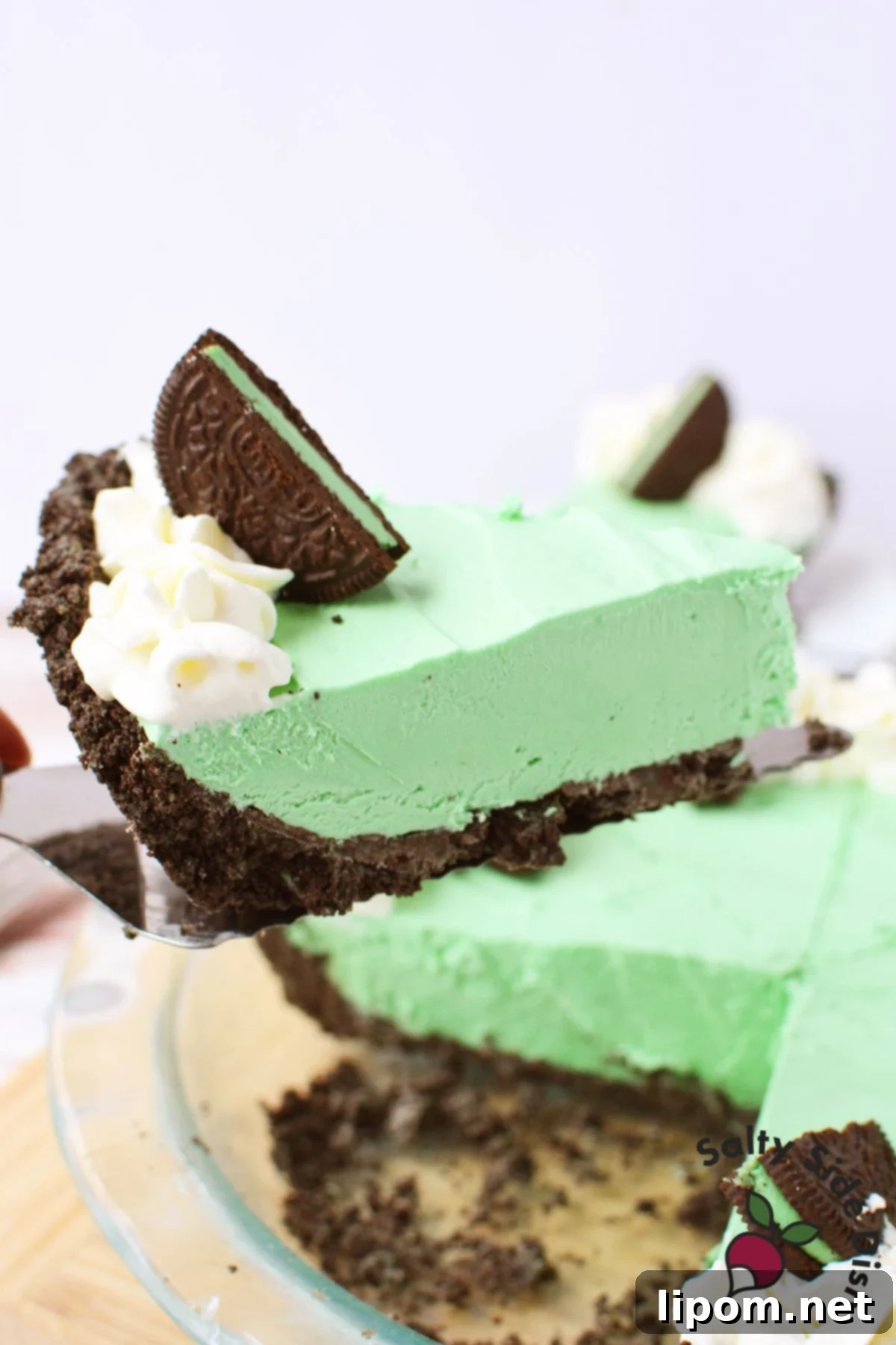 A perfectly sliced frozen grasshopper pie, showcasing its creamy, vibrant mint-green filling and dark Oreo crust, ready to be enjoyed.