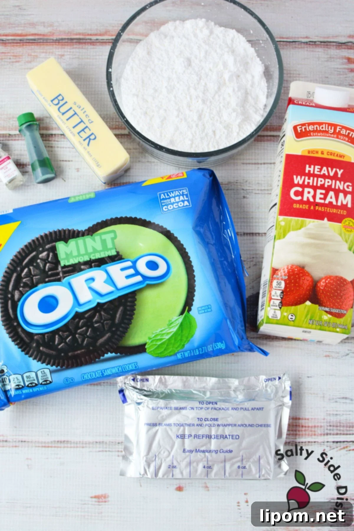 Various ingredients for a no-bake Grasshopper Pie laid out, including a family-size package of Mint Oreos, cream cheese, butter, and heavy whipping cream.